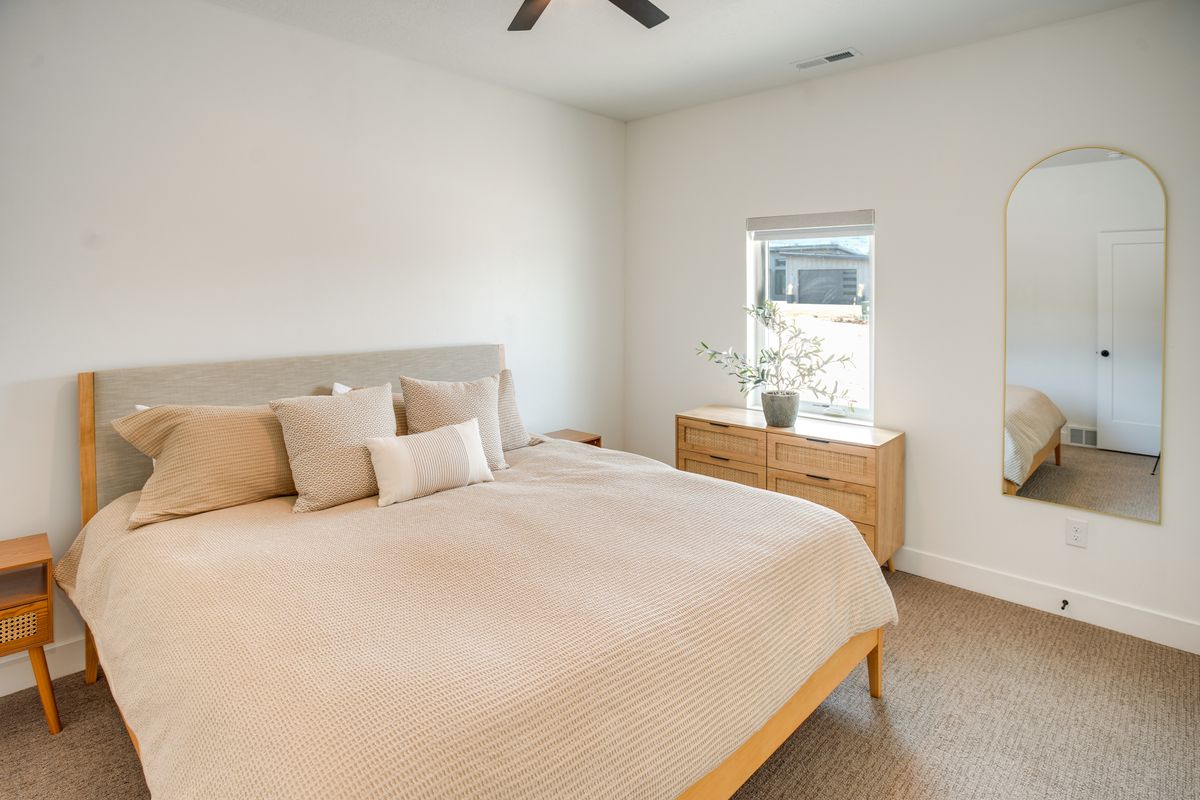 Expansive bedroom featuring neutral wall tones, textured carpeting, and a ceiling fan