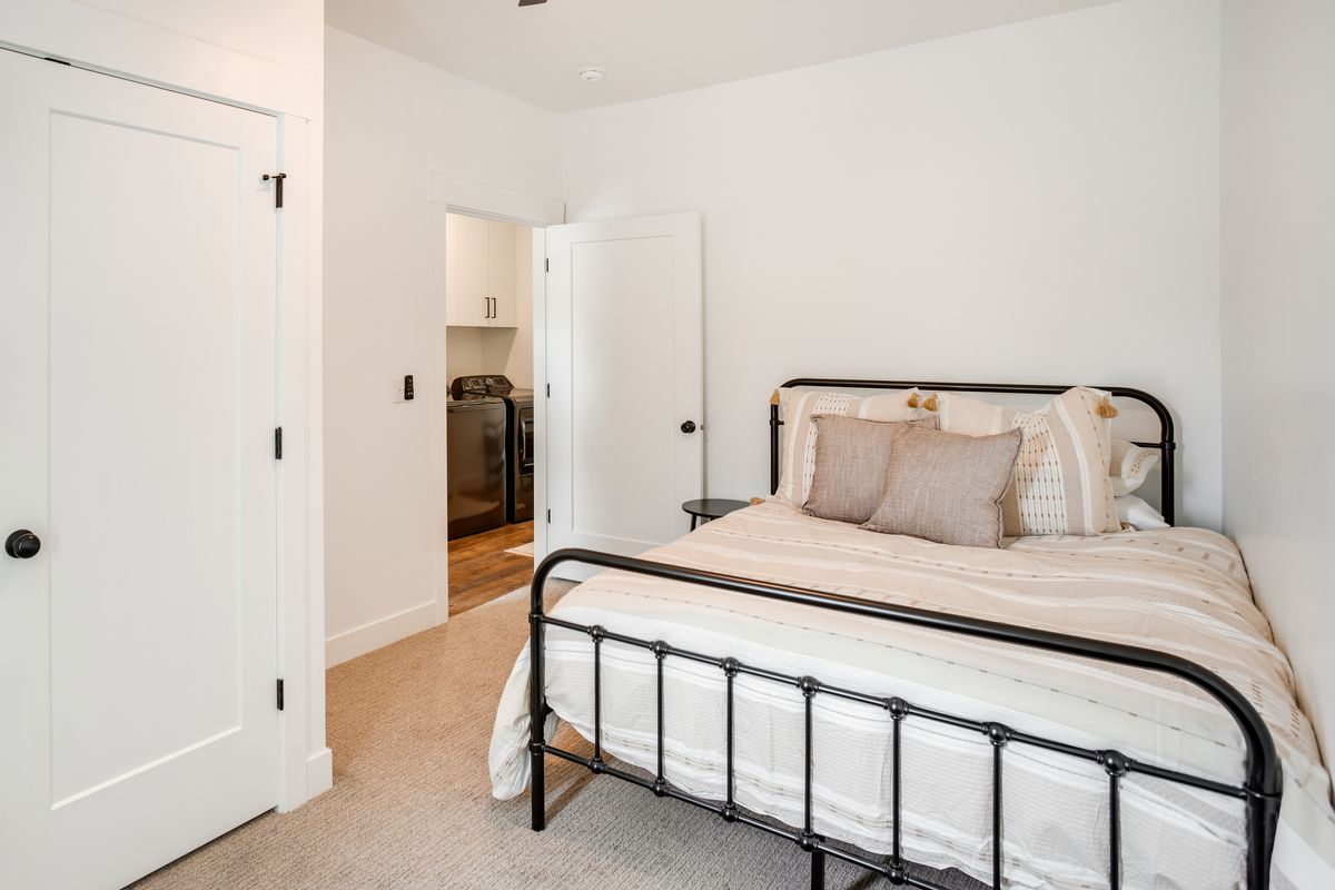Bedroom featuring light-toned carpet flooring and a flat-panel interior door with matte black hardware