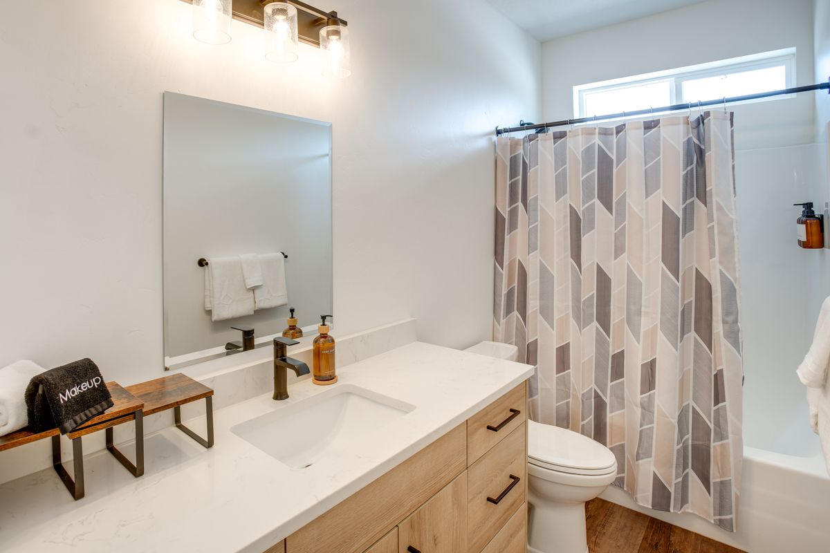 Bathroom featuring a wood-finish vanity with a white countertop and integrated sink, bronze-finish faucet, and coordinating light fixture