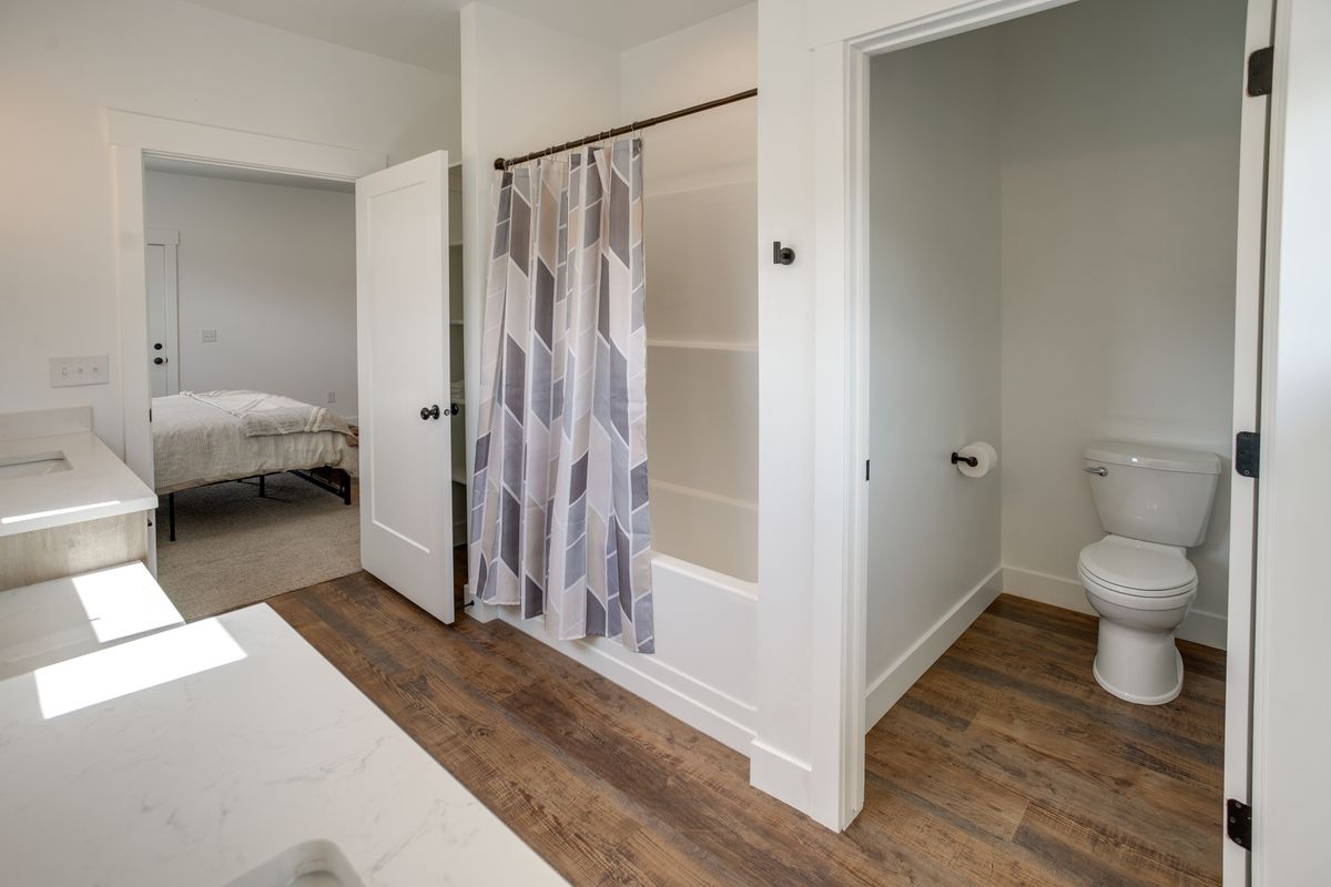 Bathroom featuring wood-finish flooring, a white vanity with a light-colored countertop, and a shower-tub combination