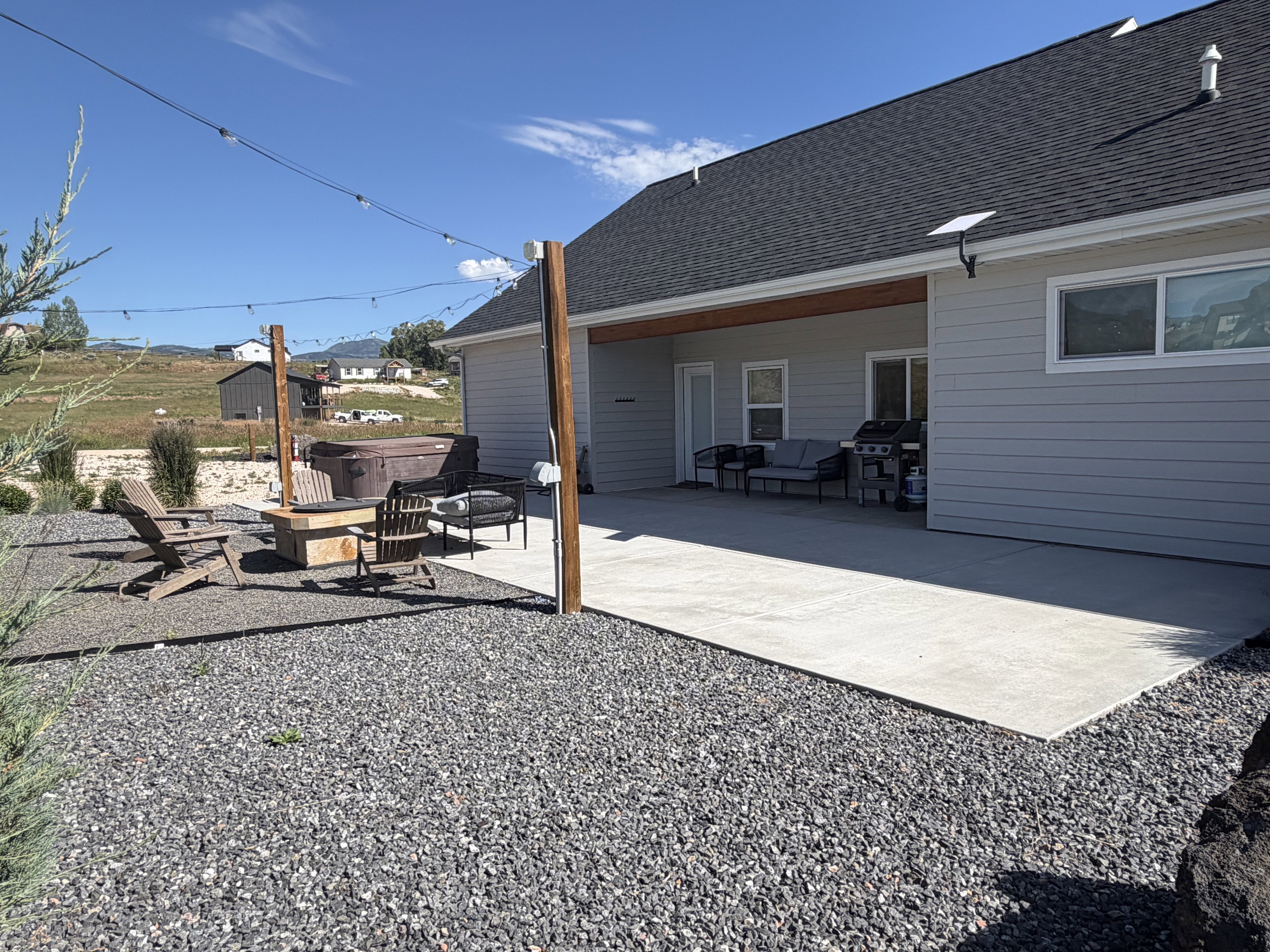 Expansive backyard featuring a large concrete patio, gravel landscaping, and a built-in fire pit