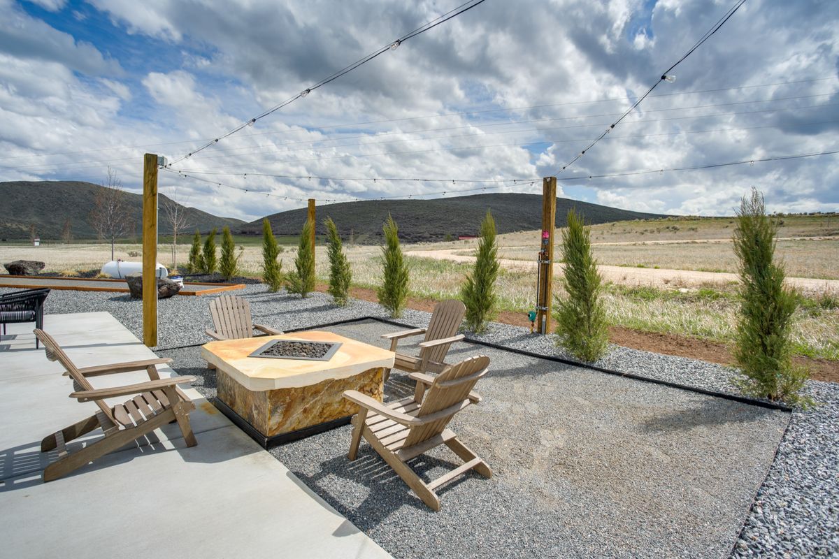 Outdoor patio featuring a built-in stone fire pit, string lighting, and gravel landscaping