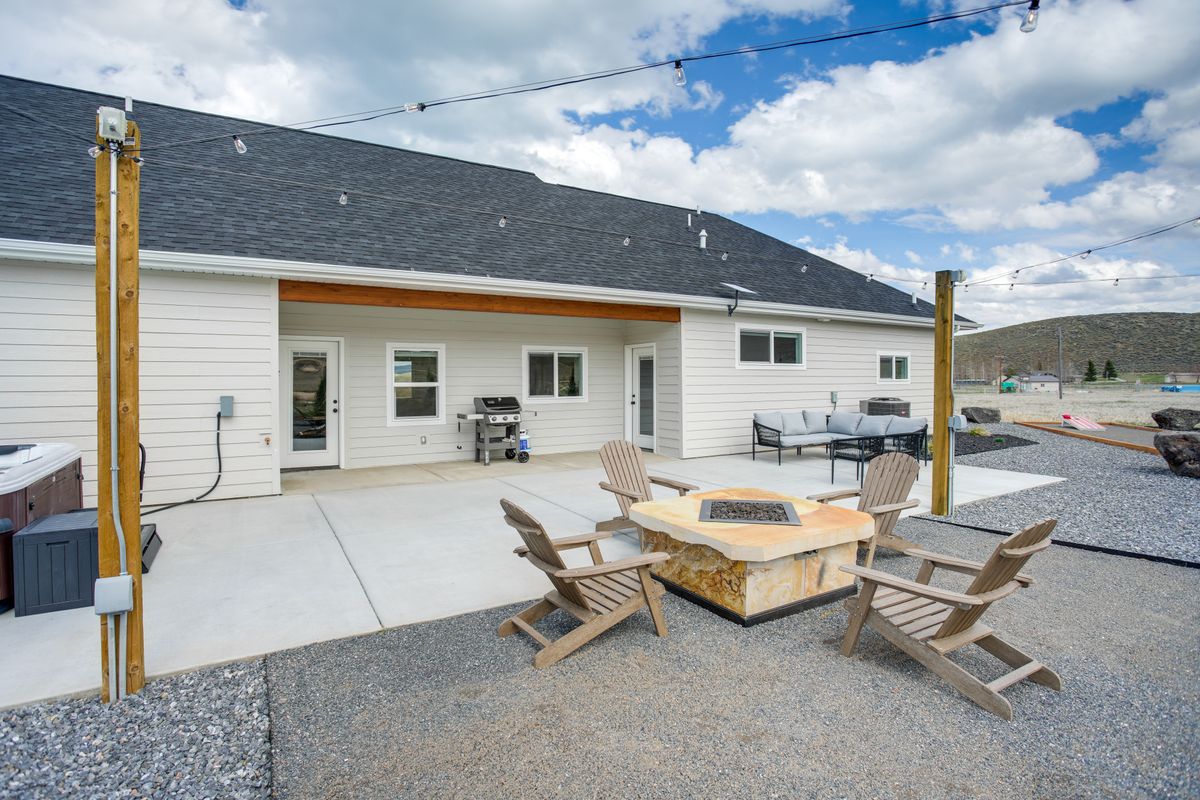 Expansive outdoor living area featuring a large concrete patio, integrated fire pit, and surrounding gravel landscaping