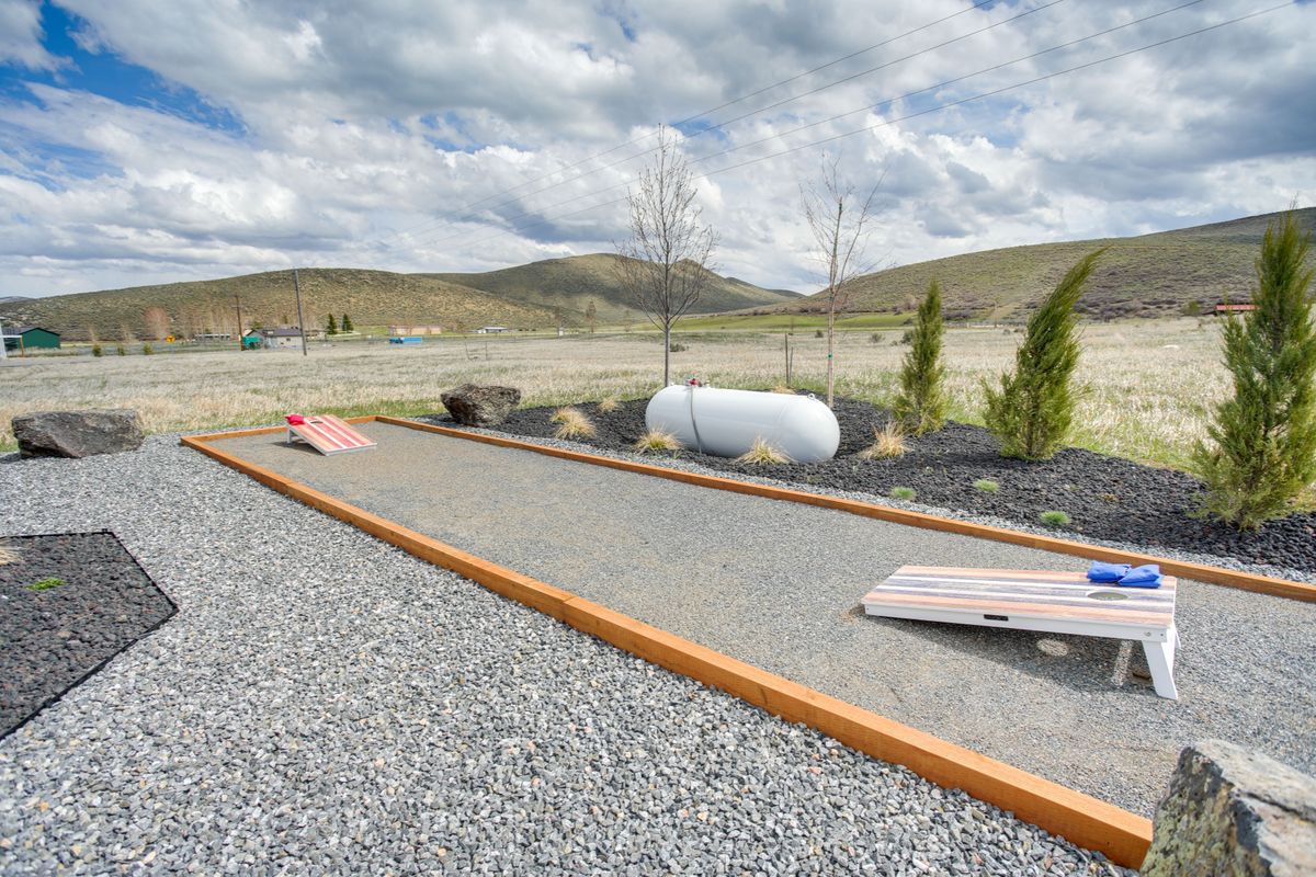 Gravel amenity area featuring a bocce ball court with wood borders, surrounded by decorative rock landscaping