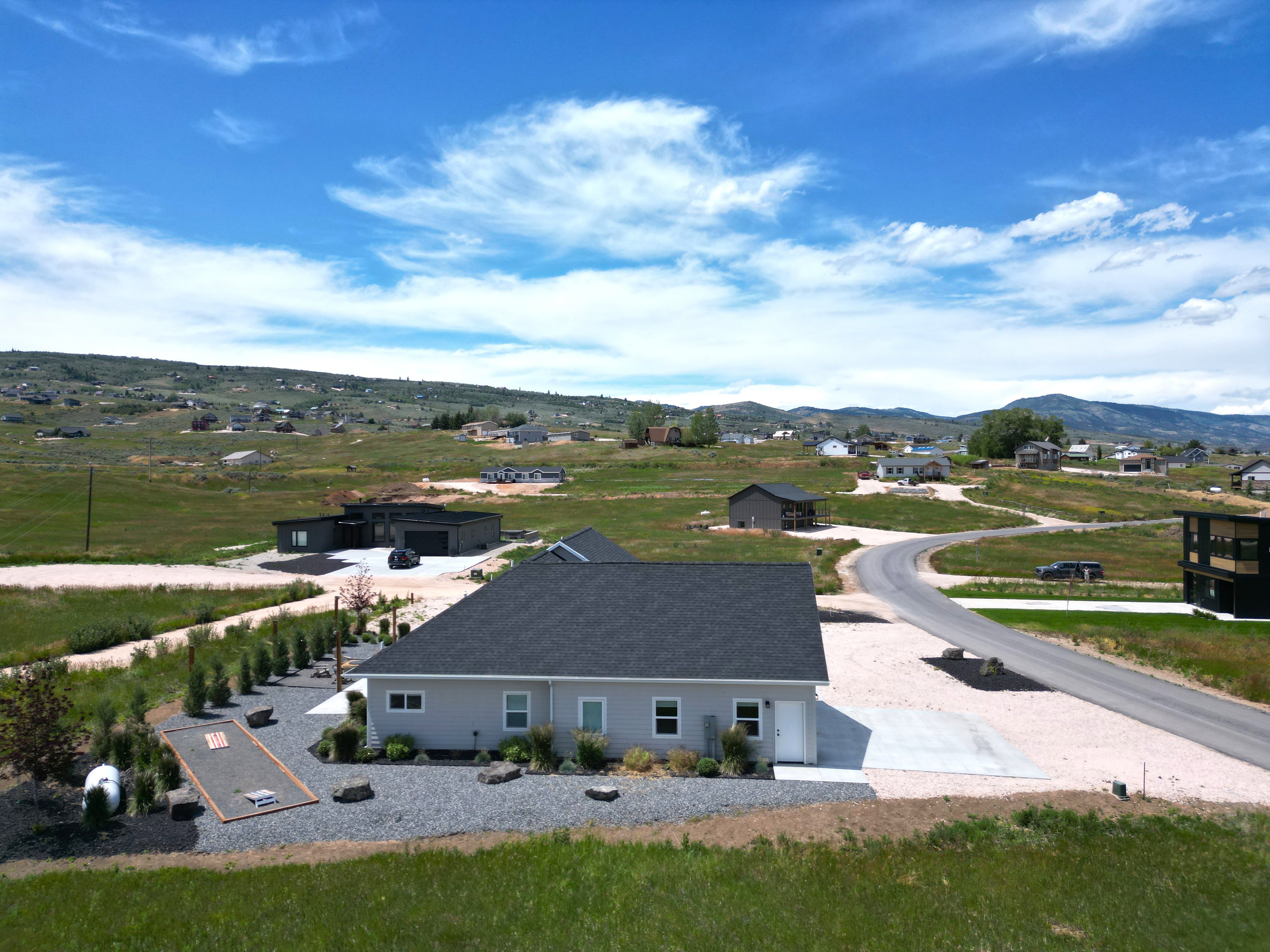 Single-story residence featuring light gray siding, dark shingle roof, and a concrete driveway