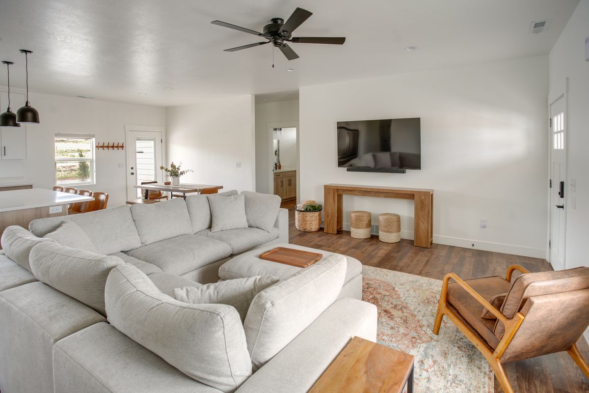 Open-concept living space featuring wood-finish flooring, a contemporary ceiling fan, recessed lighting, and a white paneled entry door