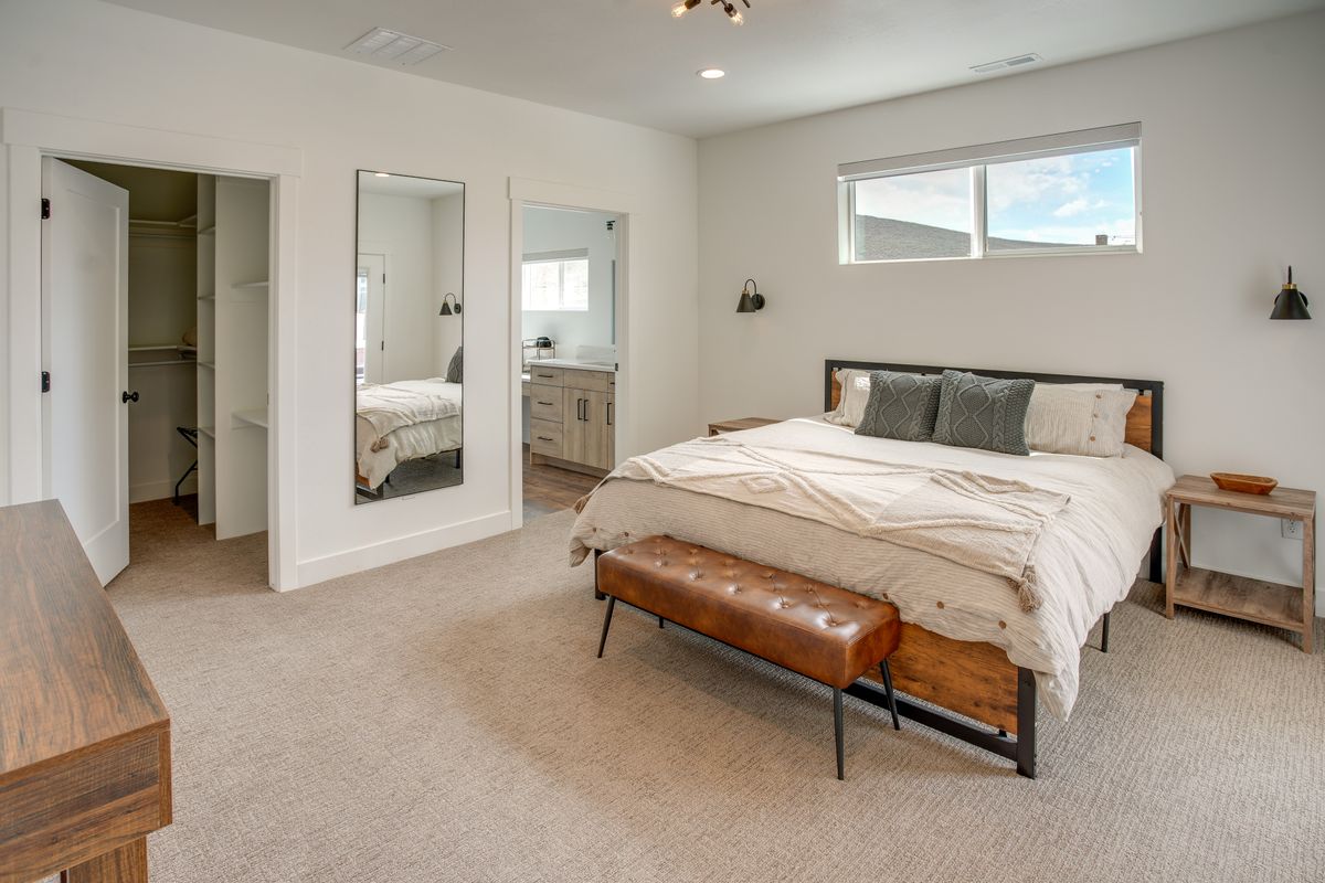 Carpeted bedroom with a large window and two industrial-style sconces