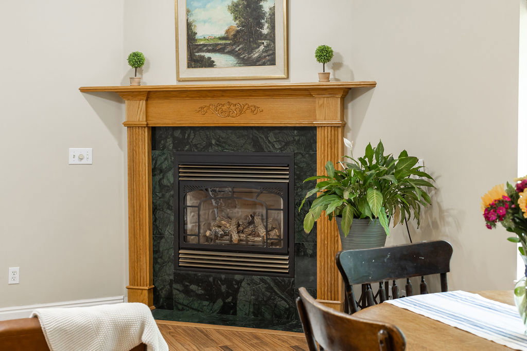 Natural fireplace featuring a wood mantel with carved detailing, green stone surround, and a black firebox