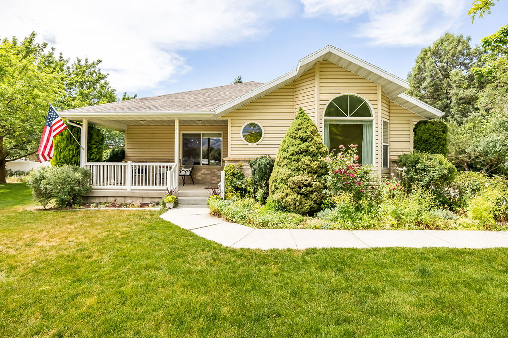 Single-story home featuring light-colored siding and a covered front porch with white railing