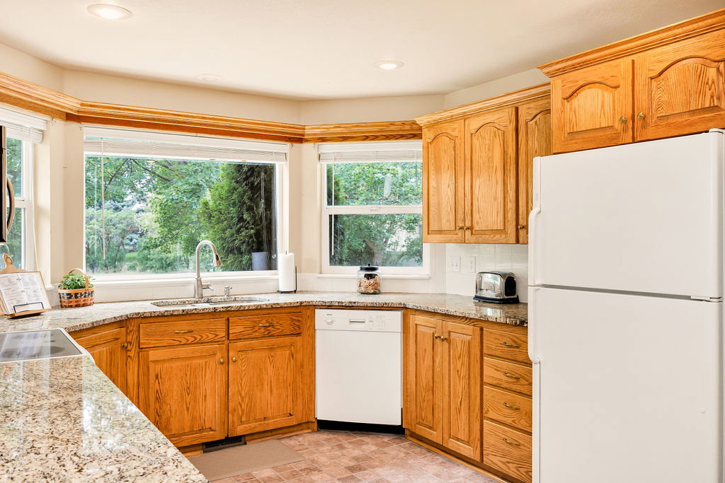Kitchen featuring wood cabinetry, granite countertops, and a bay window over the sink