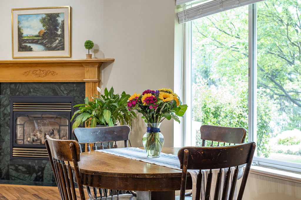 Light wood mantelpiece with decorative carving above a fireplace insert framed by dark green stone surround