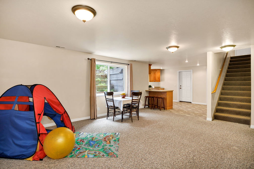 Spacious lower level featuring light-toned walls, recessed lighting, and a window with natural light and lovely terraced flower beds in the window well