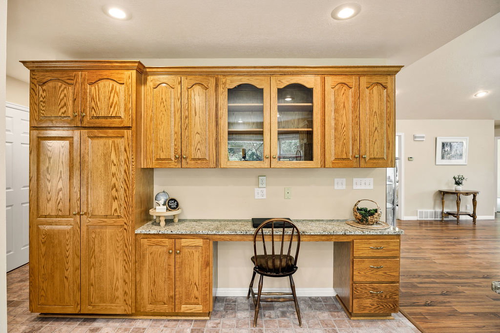 Built-in wood cabinetry with glass-front display cabinets, integrated desk space, and recessed lighting