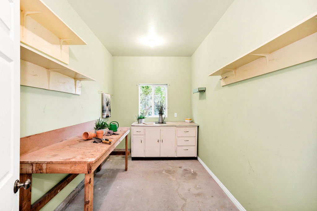 Utility room with concrete flooring, built-in lower cabinetry, and a window within the garage, could be workshop, potting room, etc.