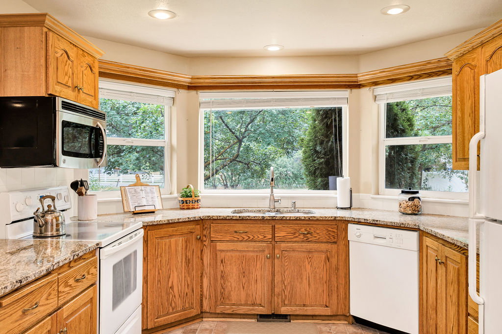 Kitchen featuring a bay window with loads of natural light, wood cabinetry, granite countertops, and recessed lighting