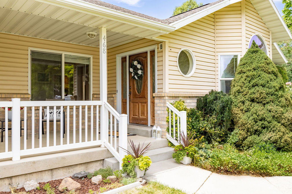 Inviting front porch entrance featuring a paneled wood-finish door, white railing, and horizontal siding