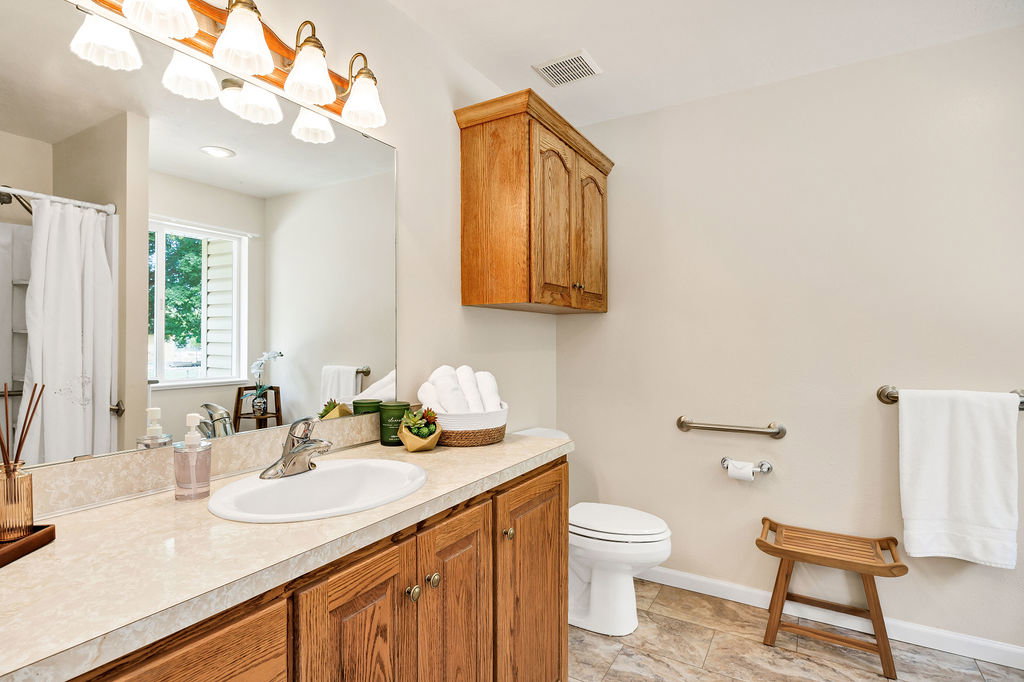Bathroom vanity featuring wood cabinetry and a large integrated mirror