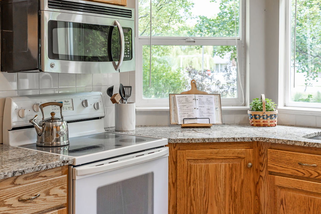 Kitchen featuring wood cabinetry, granite countertops, and a white tile backsplash