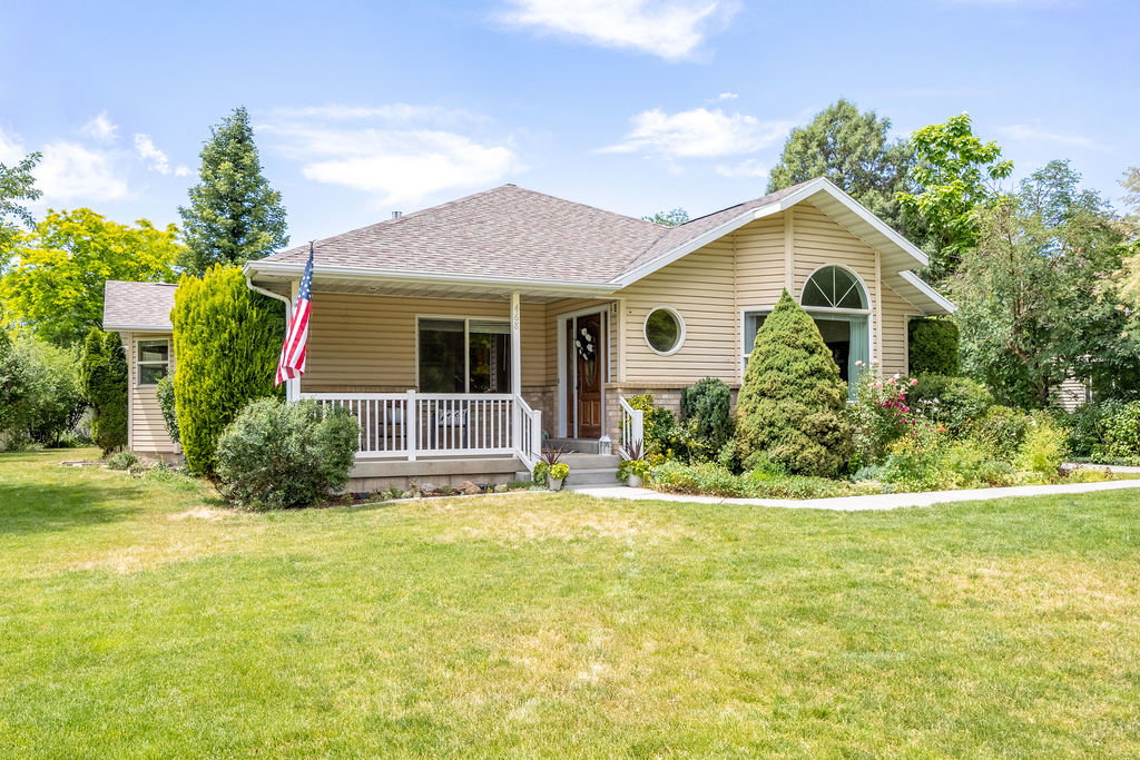 Cream-toned siding exterior with a covered porch, stone veneer accents, and a gabled roofline