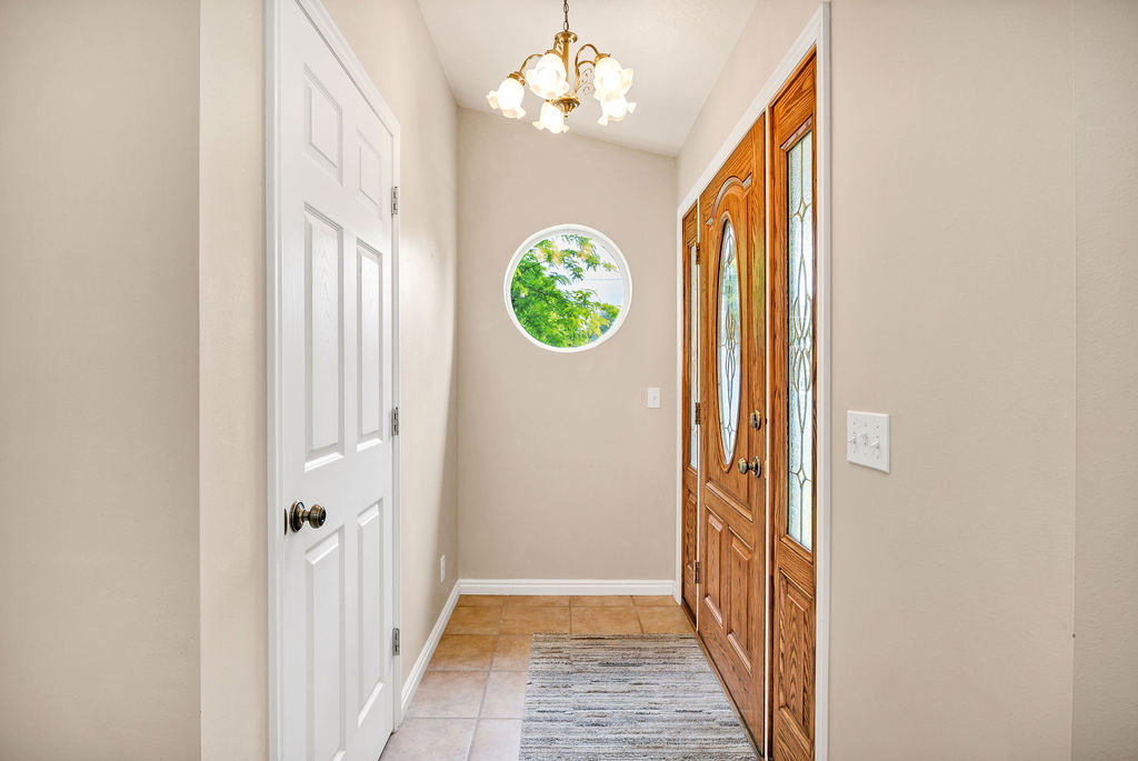 Entryway featuring a wood-panel front door with decorative glass inserts, a circular window, and ceramic tile flooring