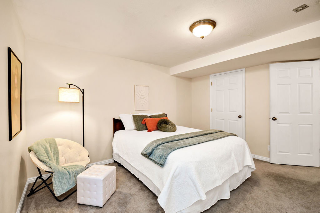 Bedroom featuring light beige walls and a domed ceiling light fixture with a large walk-in closet