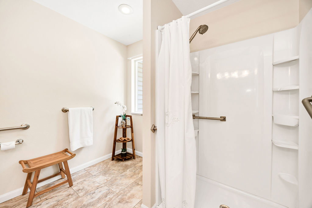 Bathroom featuring a walk-in shower enclosure with safety grab bars and space for a deep tub insert