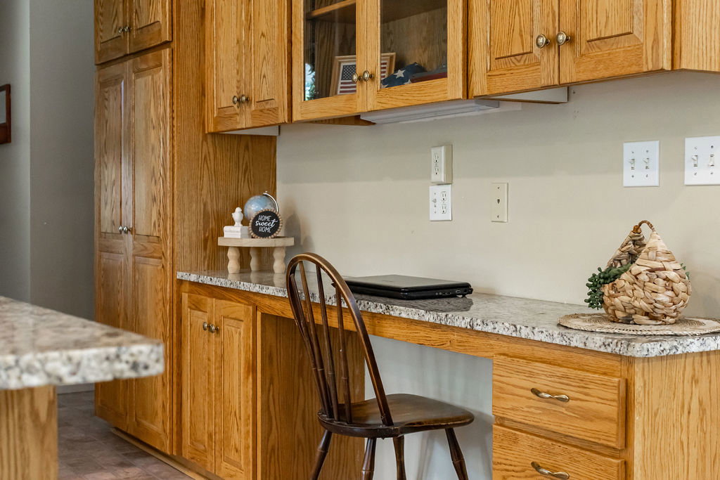 Kitchen with extensive wood cabinetry, built-in desk area, and glass-front upper cabinets