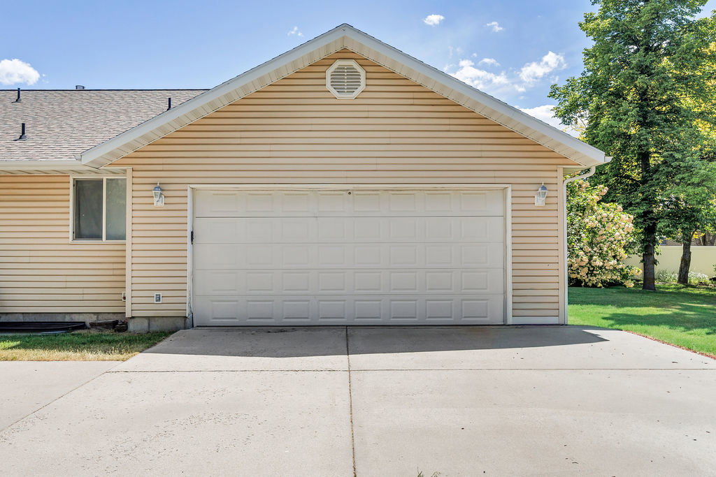 Attached garage featuring a panel-style door, horizontal vinyl siding, and a concrete driveway