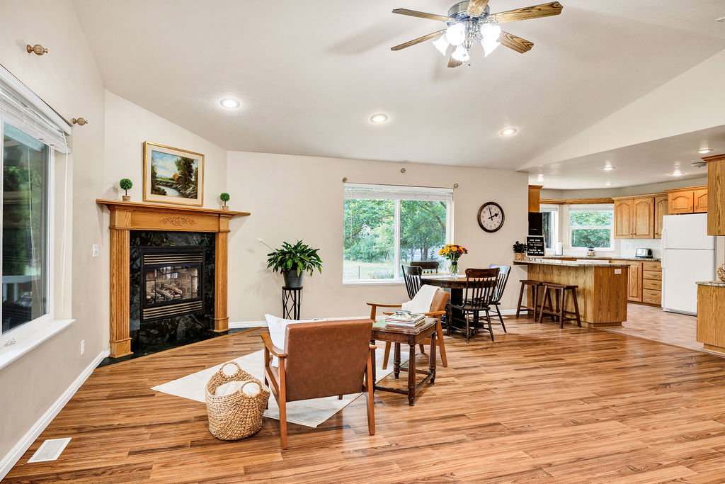 Vaulted ceiling living area featuring wood-finish flooring, a fireplace with a wood mantle and dark stone surround, and recessed lighting