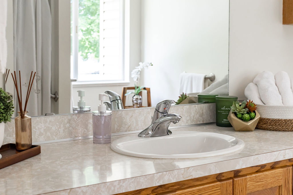 Bathroom vanity featuring an oval undermount sink with chrome fixtures, a light-toned countertop, and wood-finish cabinetry