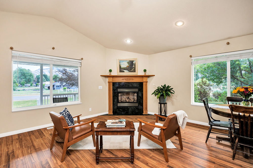 Vaulted ceilings highlight this living space, featuring wood-finish flooring and multiple windows for fabulous natural light