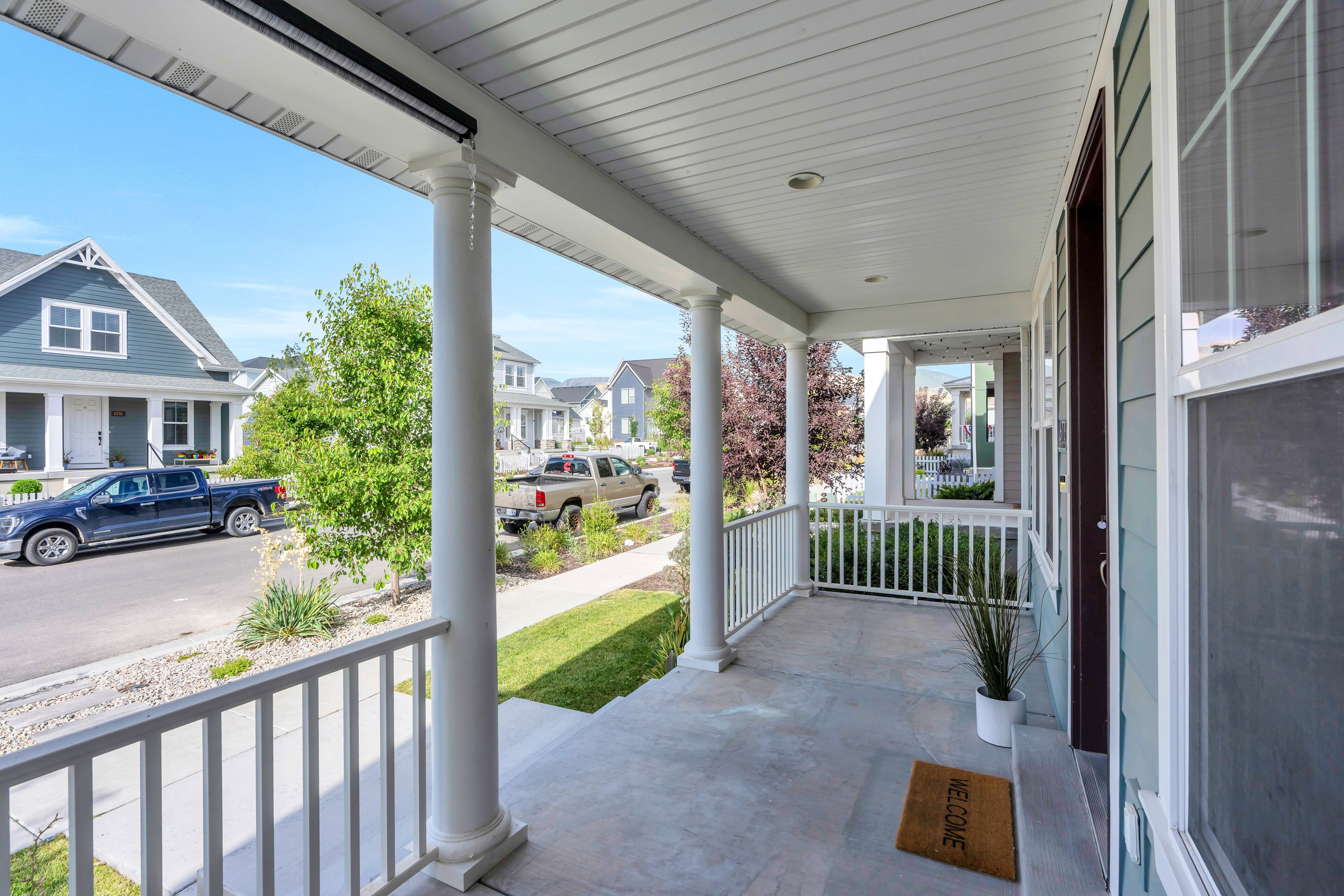 Covered front porch featuring white columns and railing, a concrete surface, and light blue siding