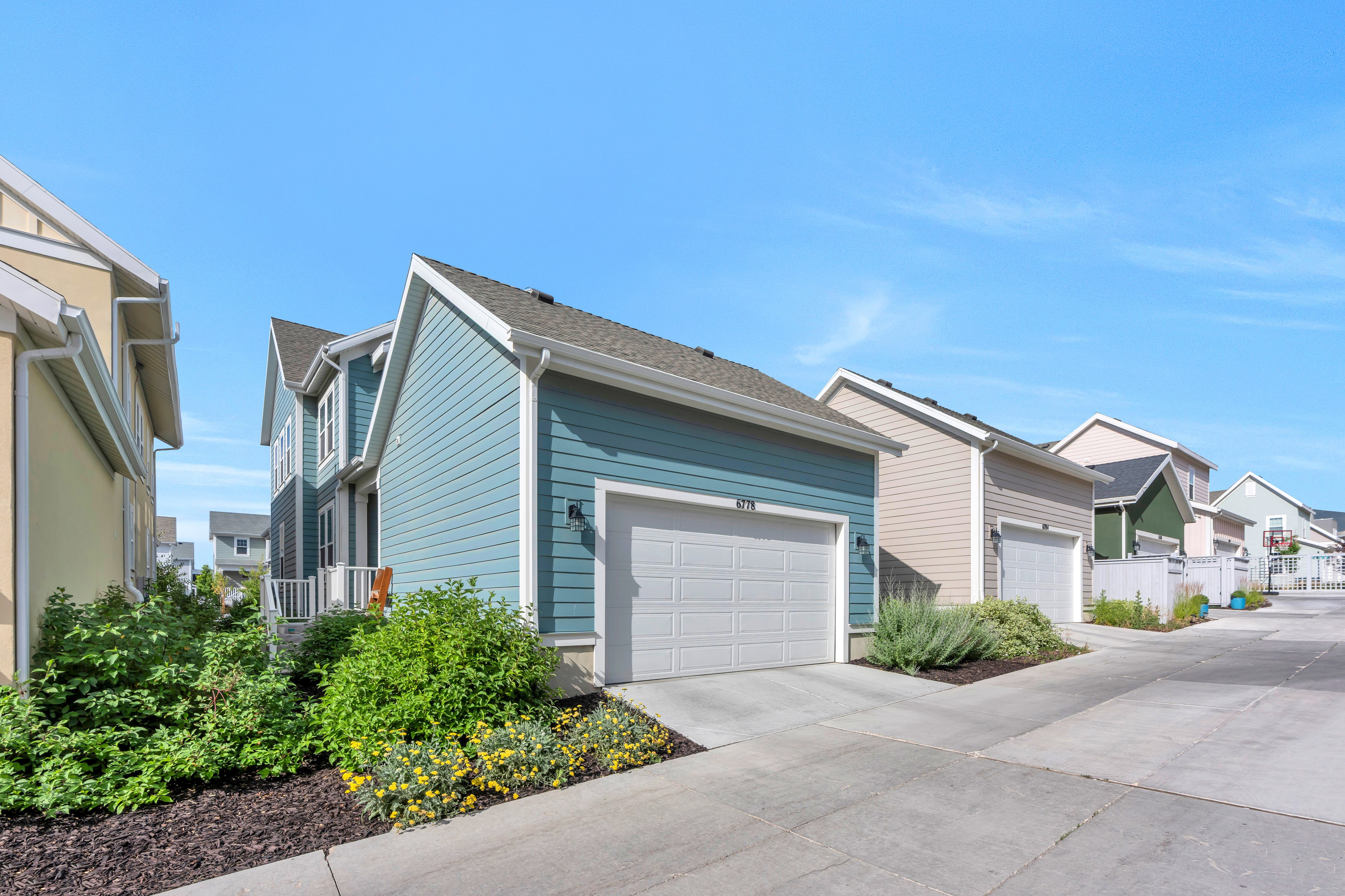 Two-story residence featuring blue siding, a white garage door, and a concrete driveway