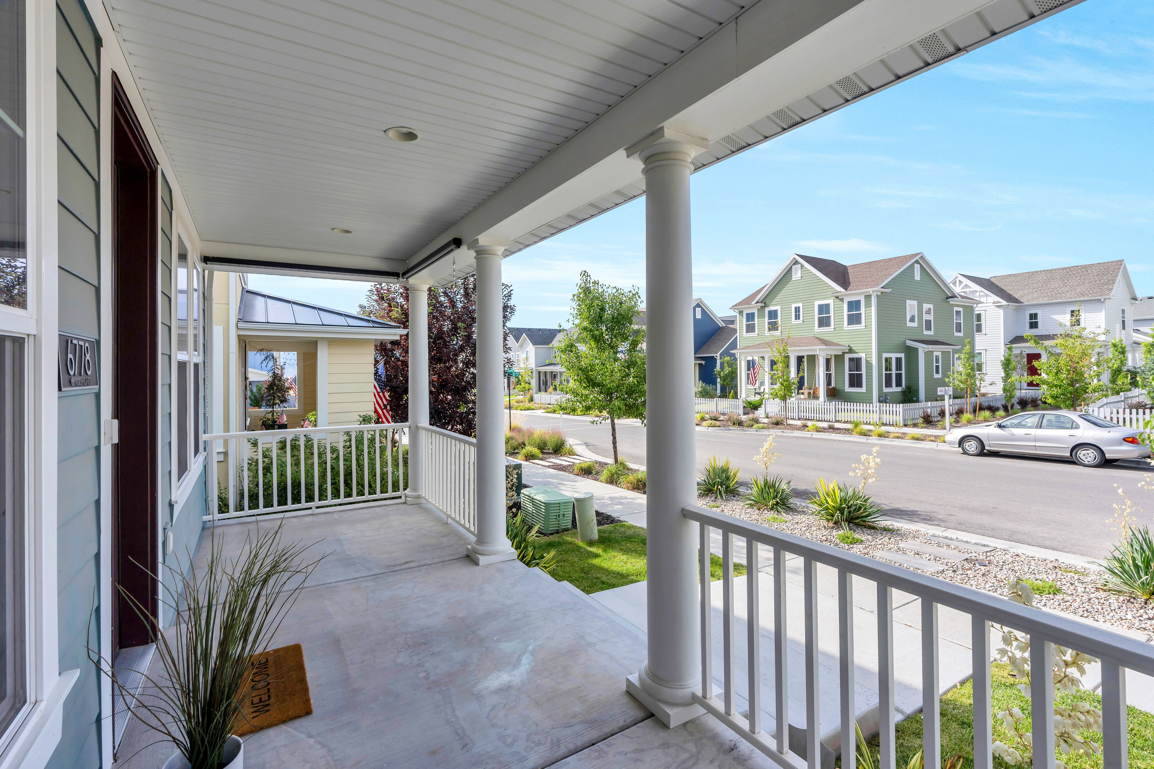 Covered concrete porch with white spindle railing and round columns