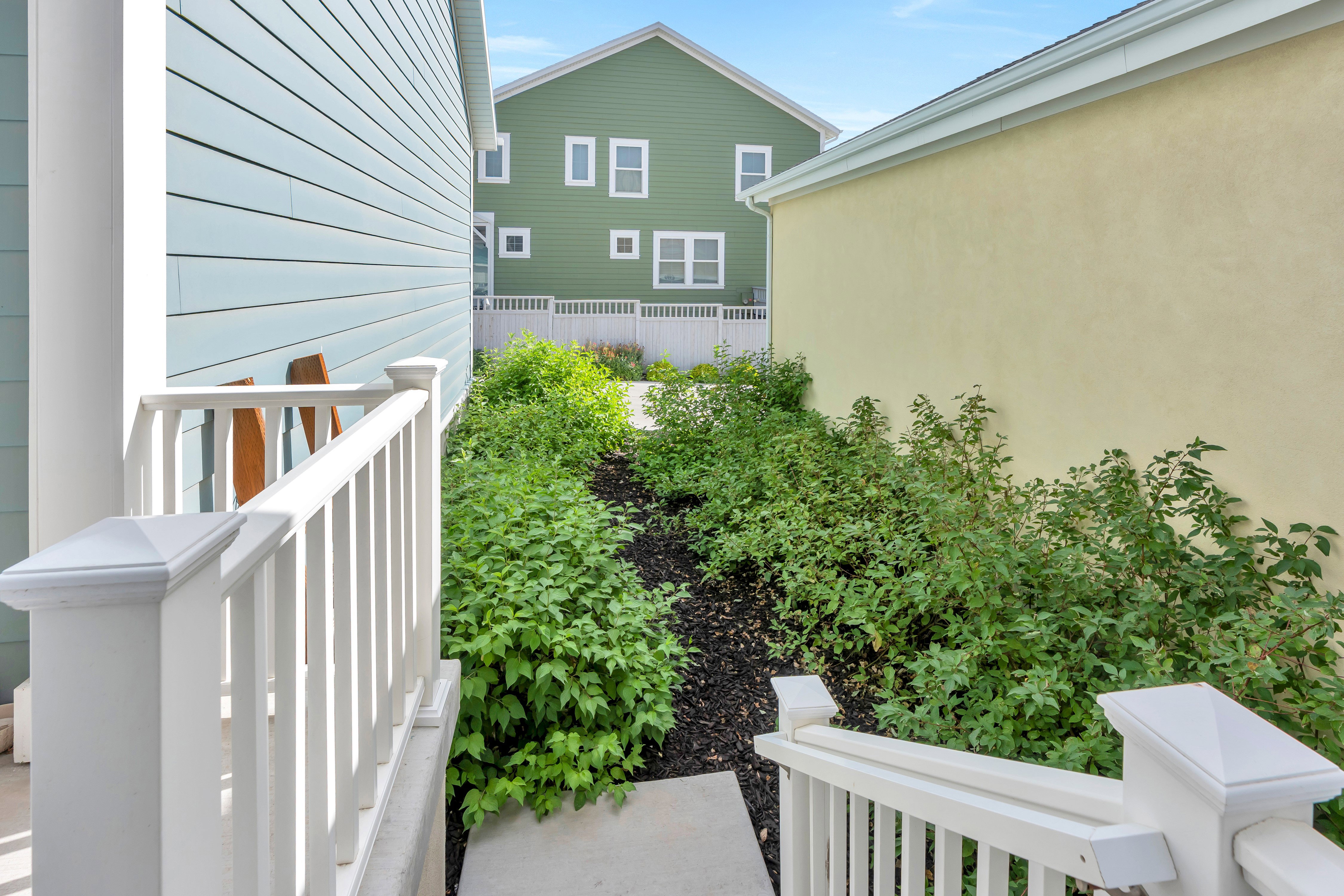 Side entry with white railing and concrete walkway