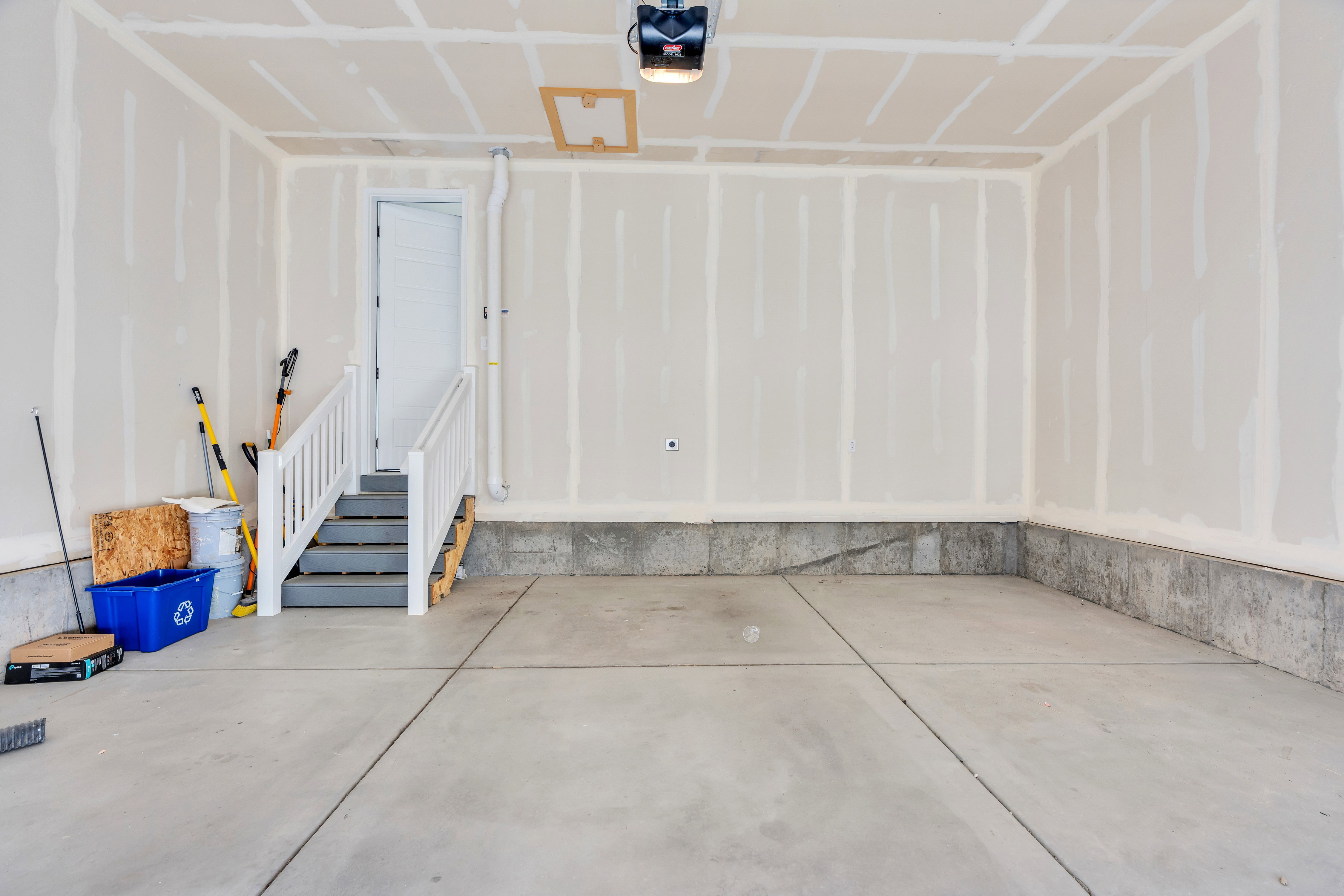 Spacious garage with concrete flooring and a built-in staircase featuring white railings