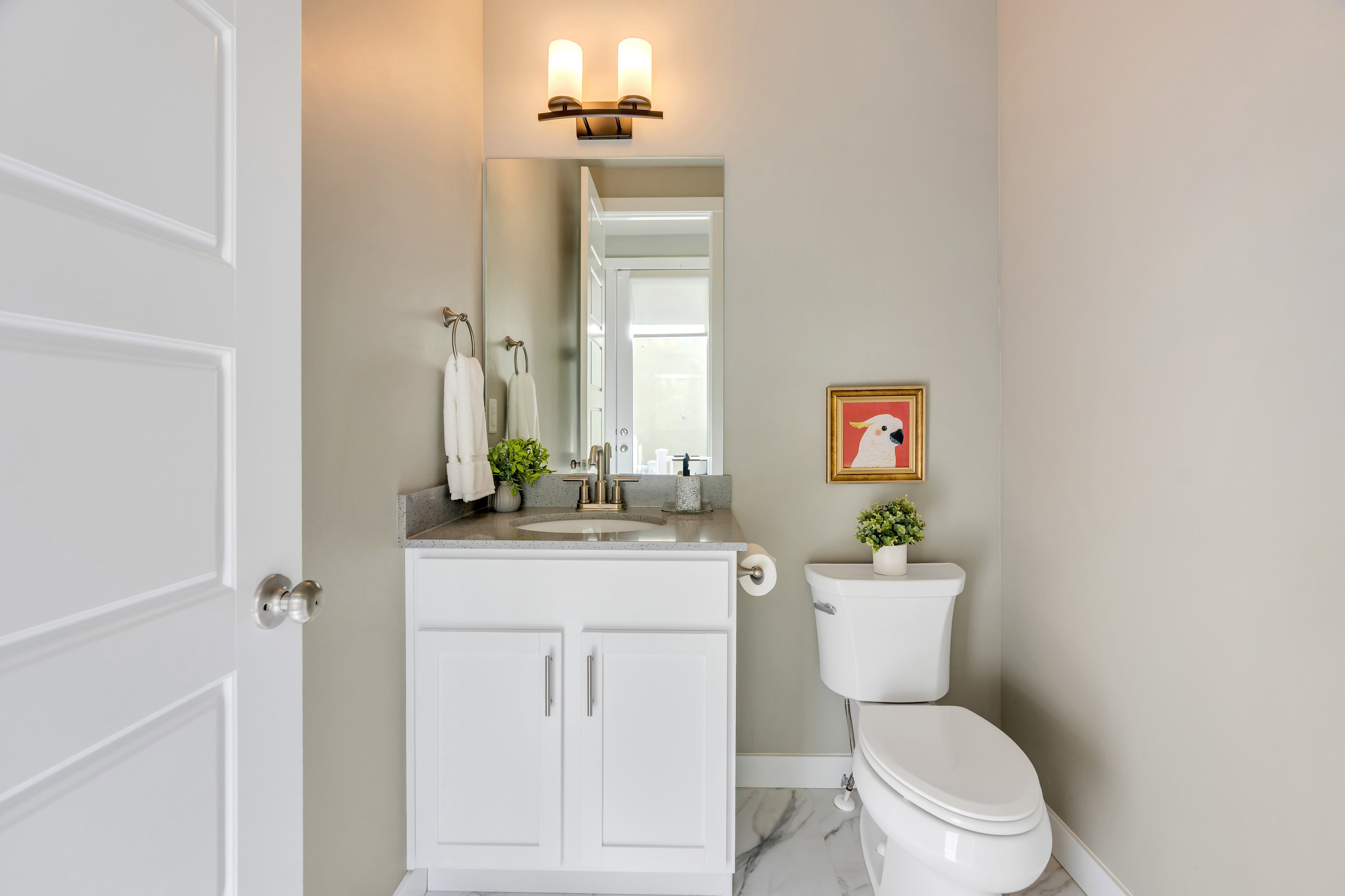 Bathroom featuring a white vanity with a stone countertop, an integrated sink, a wall-mounted mirror, and tile flooring