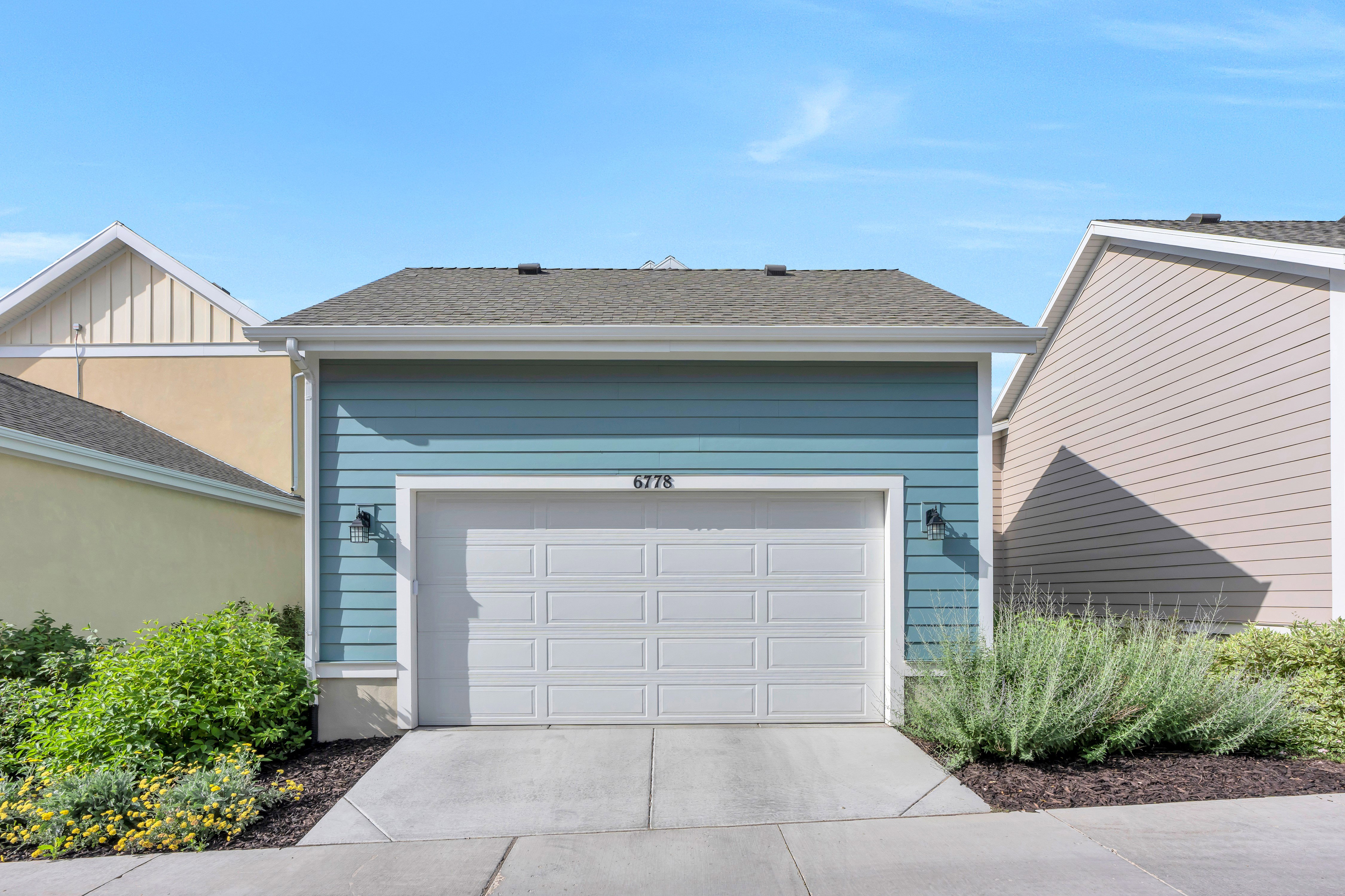 Detached garage structure featuring blue horizontal siding, a white panel garage door, and a gray shingle roof