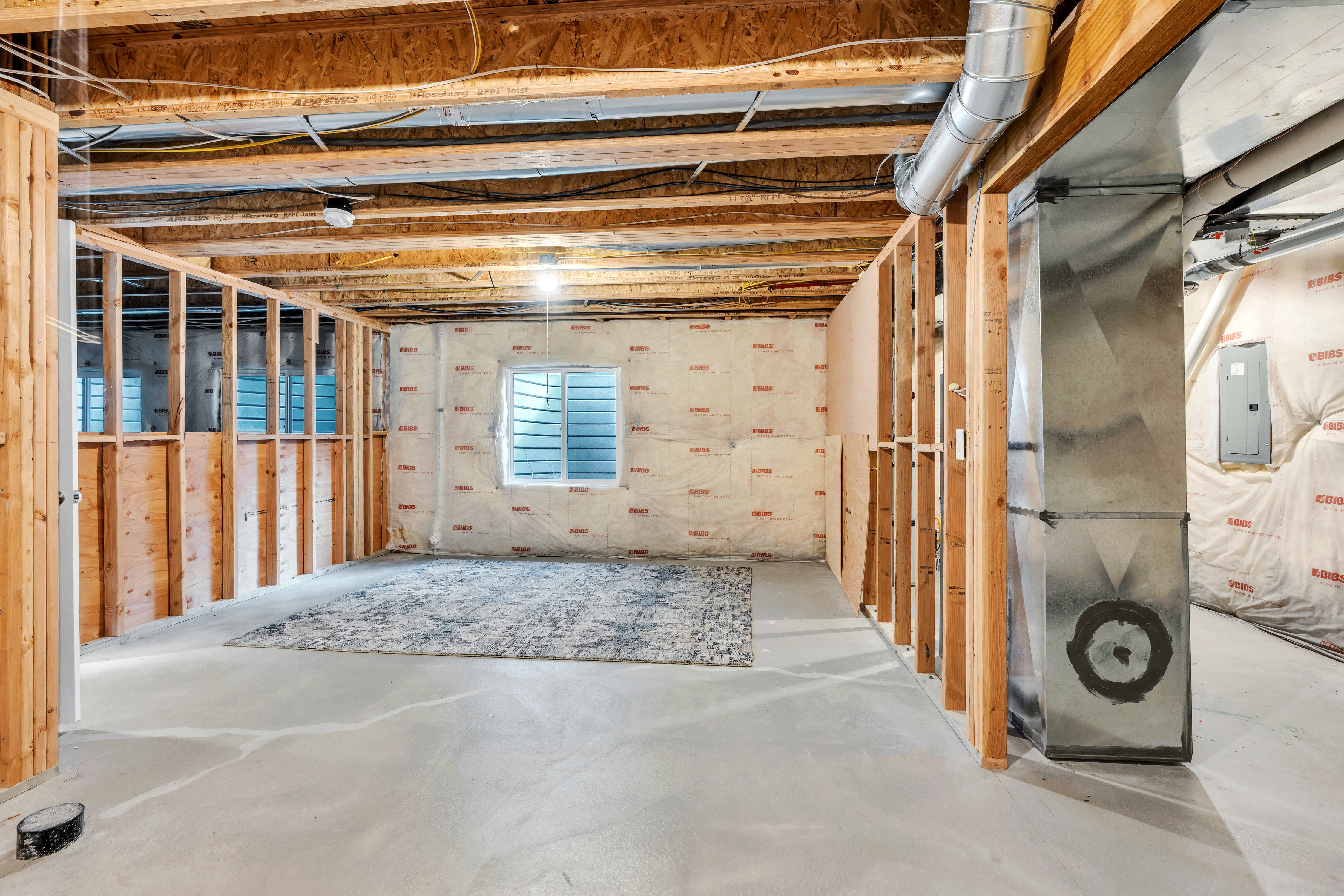 Unfinished basement featuring exposed wood framing, concrete flooring, and a single window with horizontal blinds