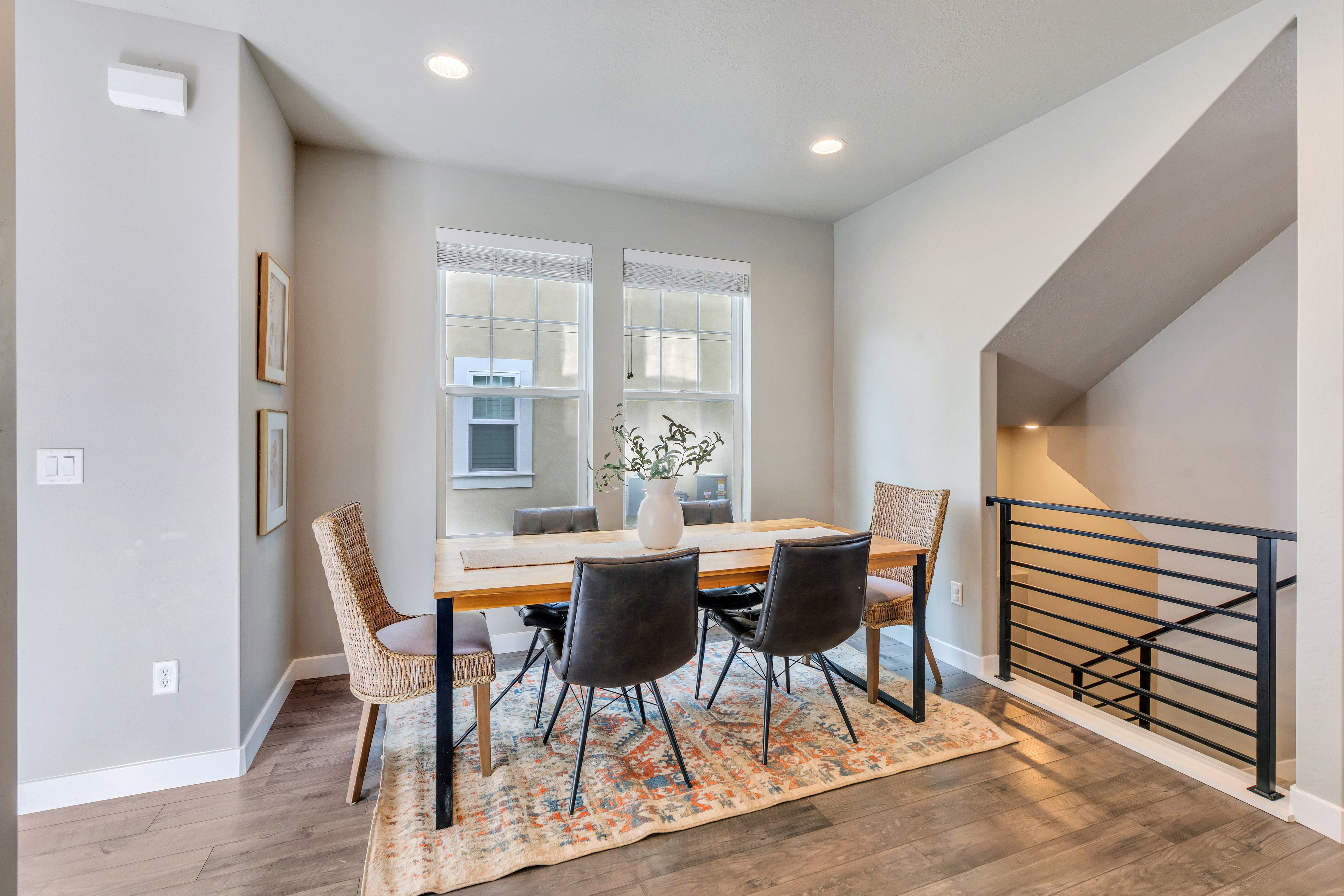 Dining area featuring wood-finish flooring, recessed lighting, and a modern horizontal metal railing