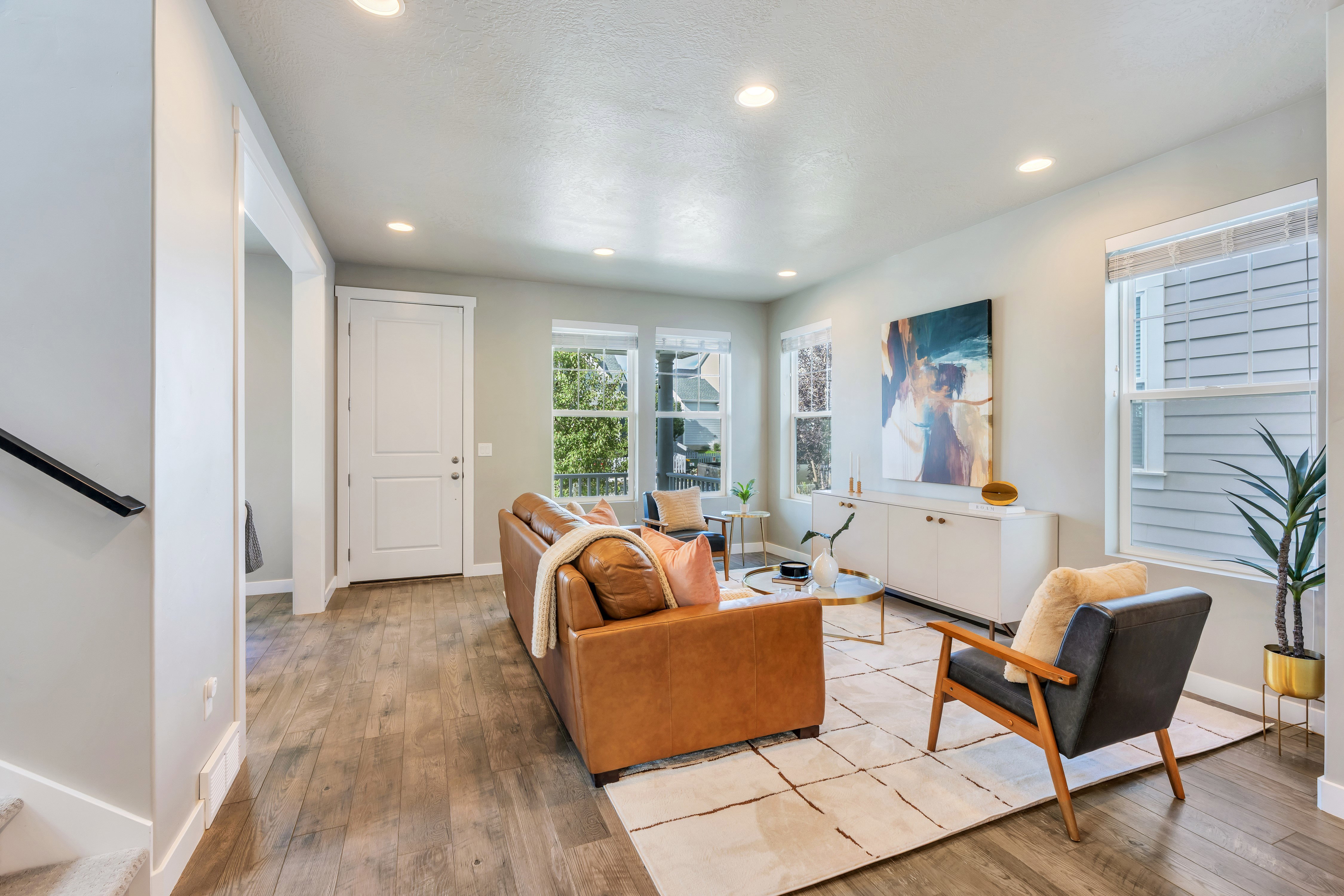 Spacious living area featuring wood-finish flooring, recessed lighting, and multiple windows for natural light