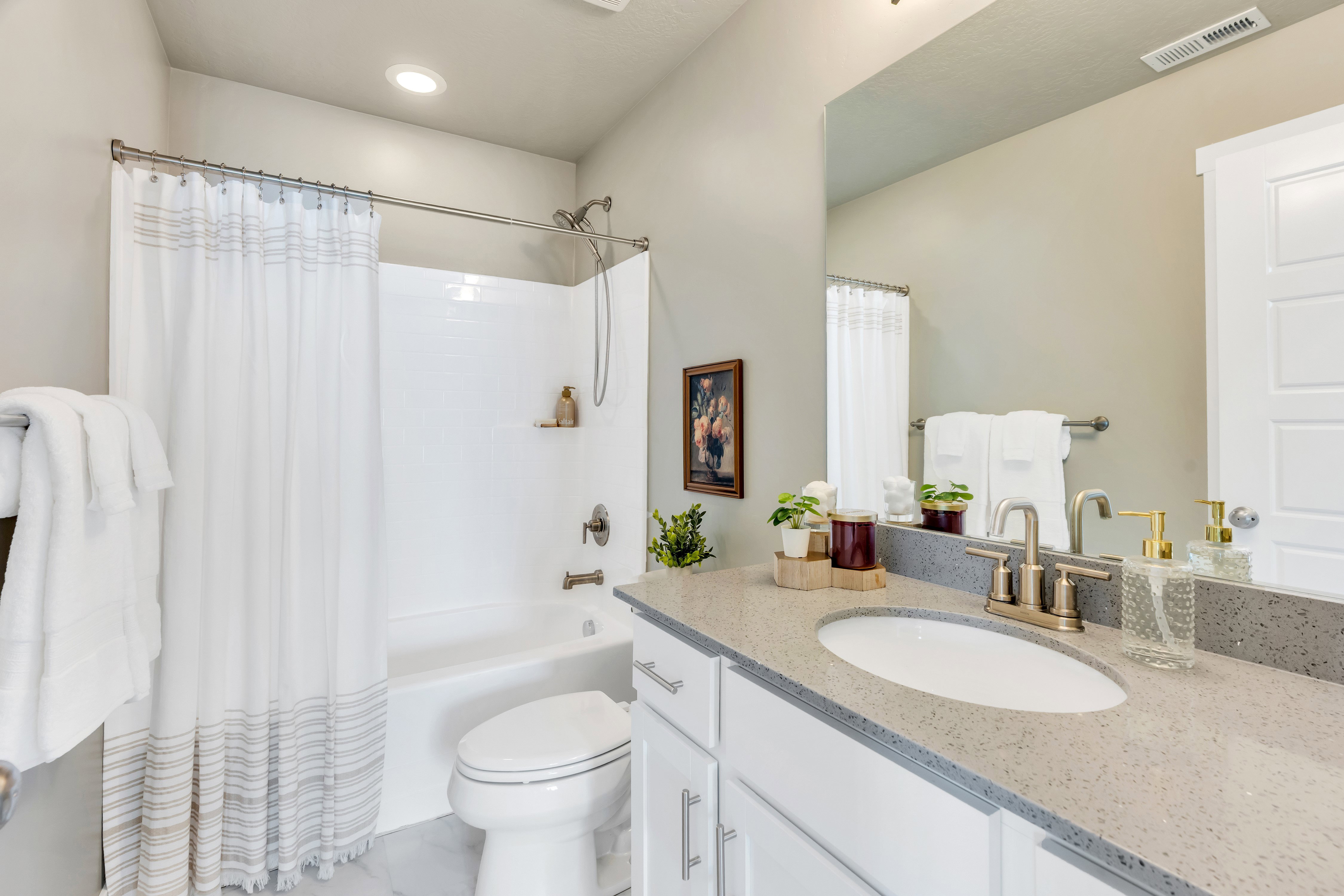 Bathroom featuring a white bathtub with a shower, a vanity with a light-colored countertop, and a large wall-mounted mirror