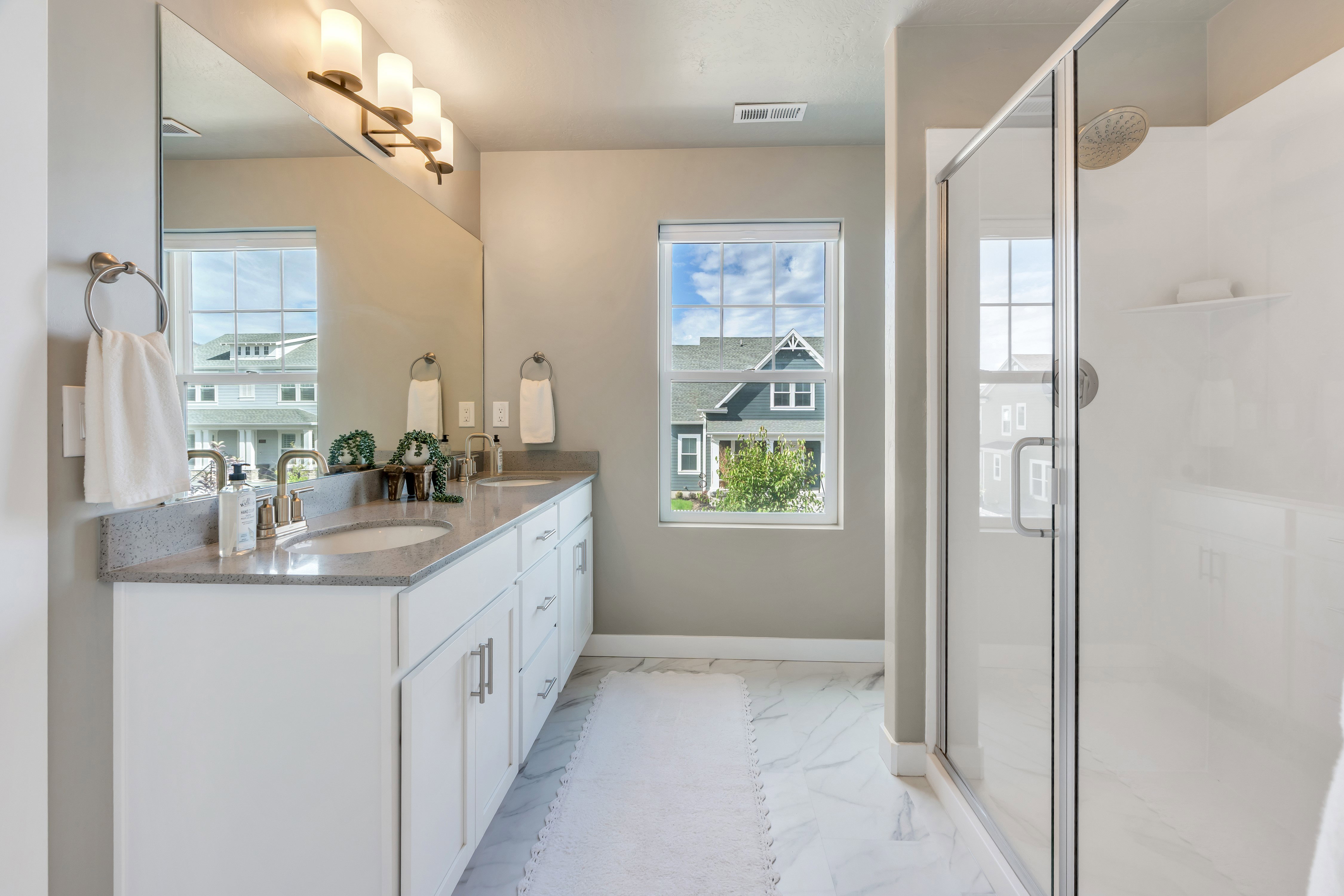Bathroom featuring a dual vanity with light-toned countertops, undermount sinks, and white cabinetry