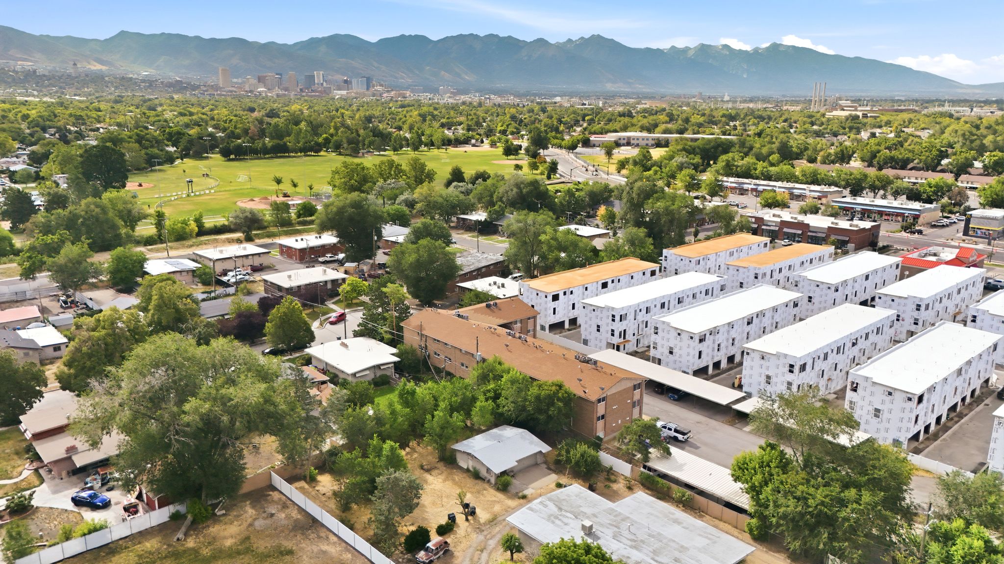 Expansive aerial view showcasing multiple residential buildings, including recently constructed multi-story structures with white exteriors