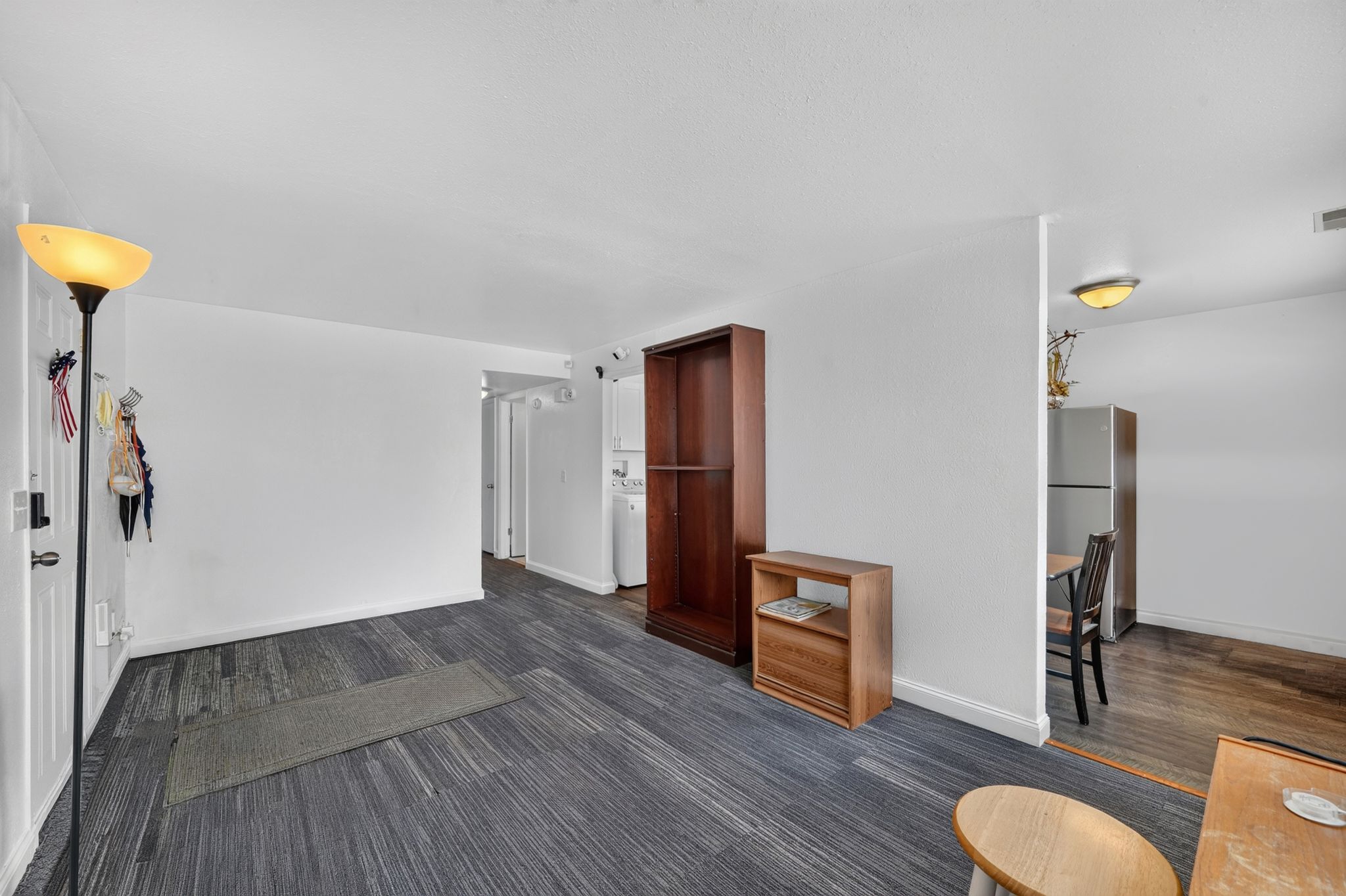 Spacious open-concept room featuring light-colored walls and wood-finish flooring