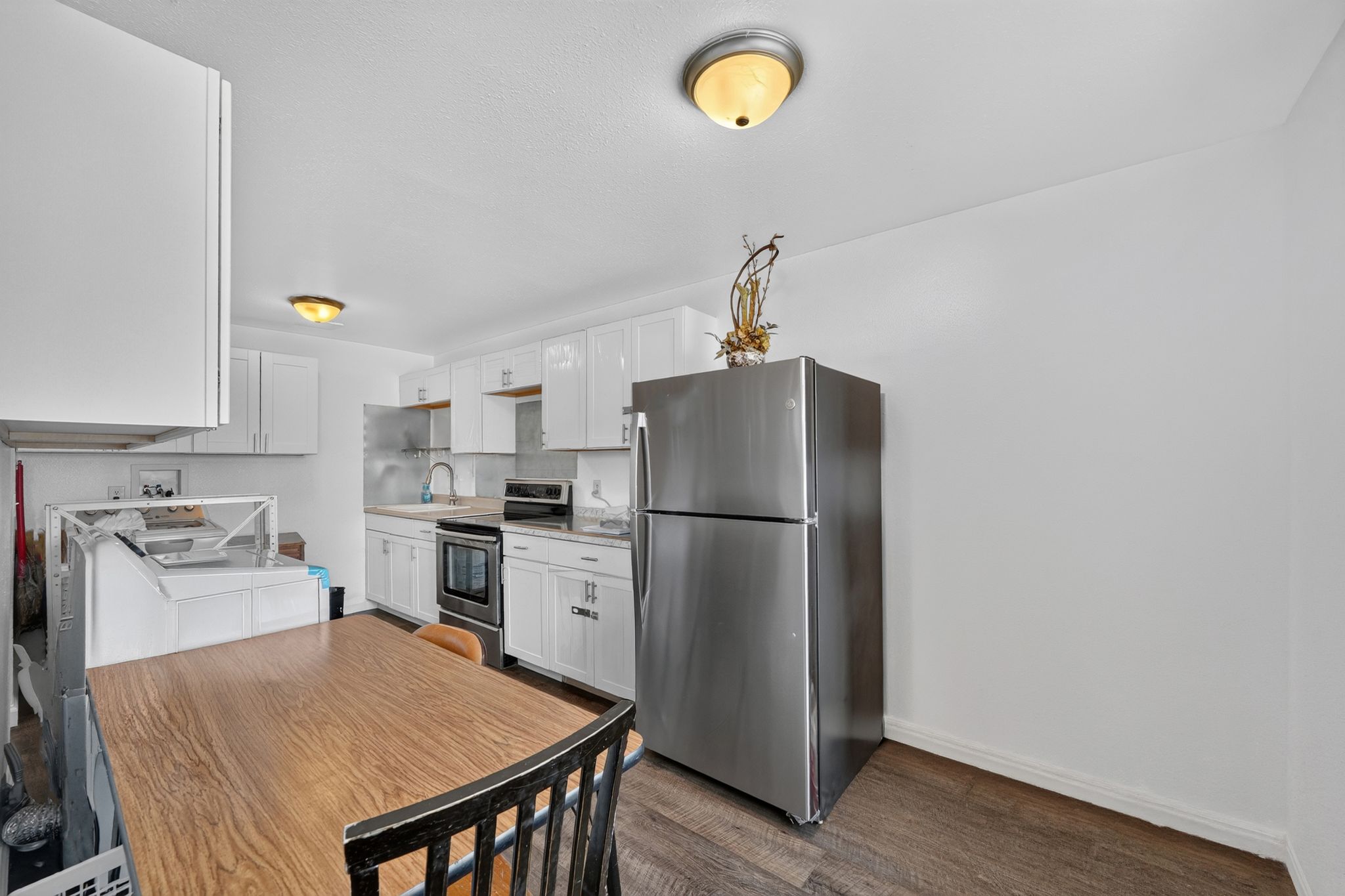 Kitchen featuring white cabinetry, stainless steel refrigerator, and wood-finish flooring