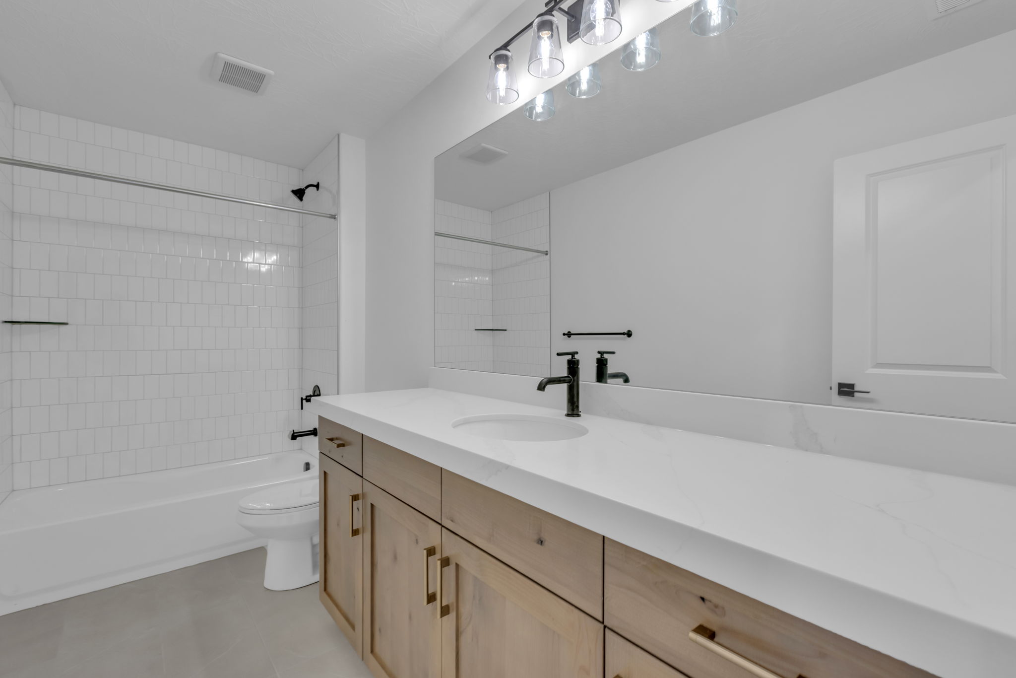 Bathroom #2, featuring a light wood-finish vanity with gold-tone hardware, a white Quartz countertop, and a large wall-mounted mirror.