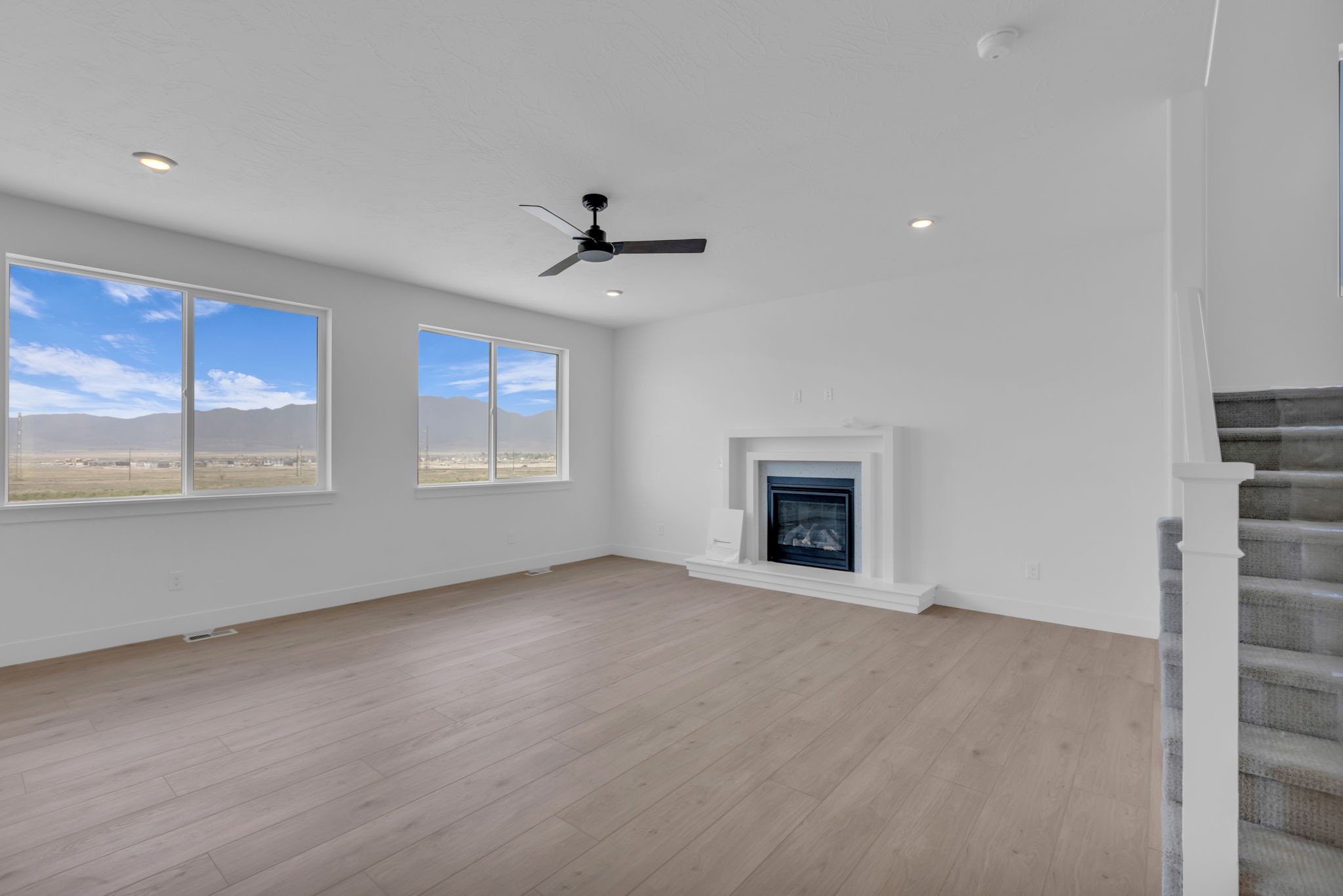 Open living space featuring a central fireplace with a white mantel with tile trim and low hearth. Large windows with beautiful mountain views.
