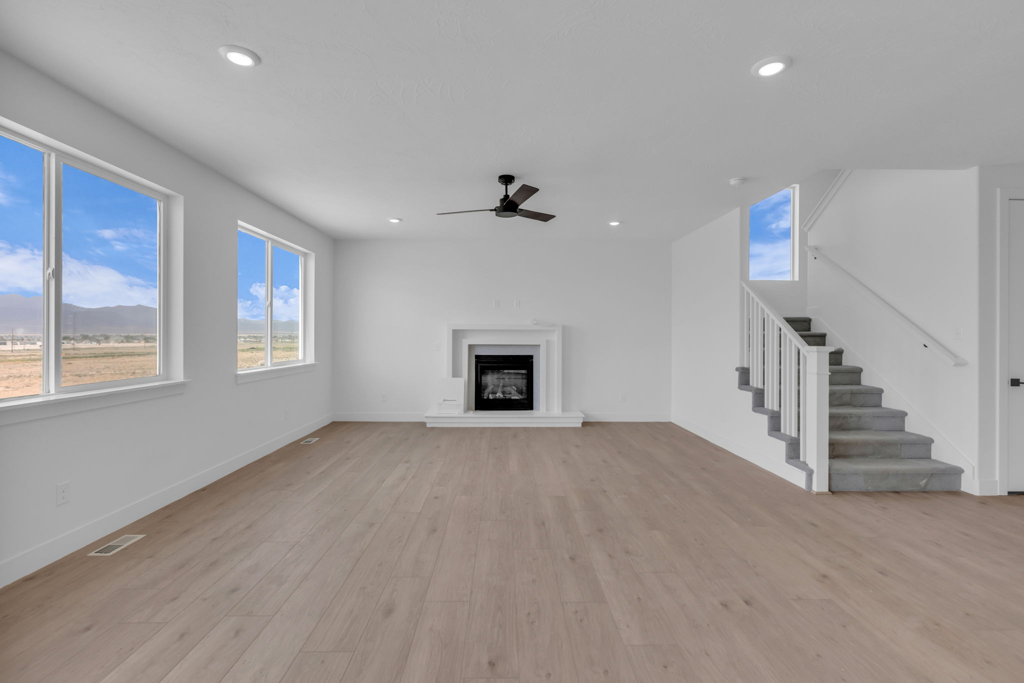 Open living space featuring a central fireplace with a white mantel with tile trim and low hearth. Large windows with beautiful mountain views.
