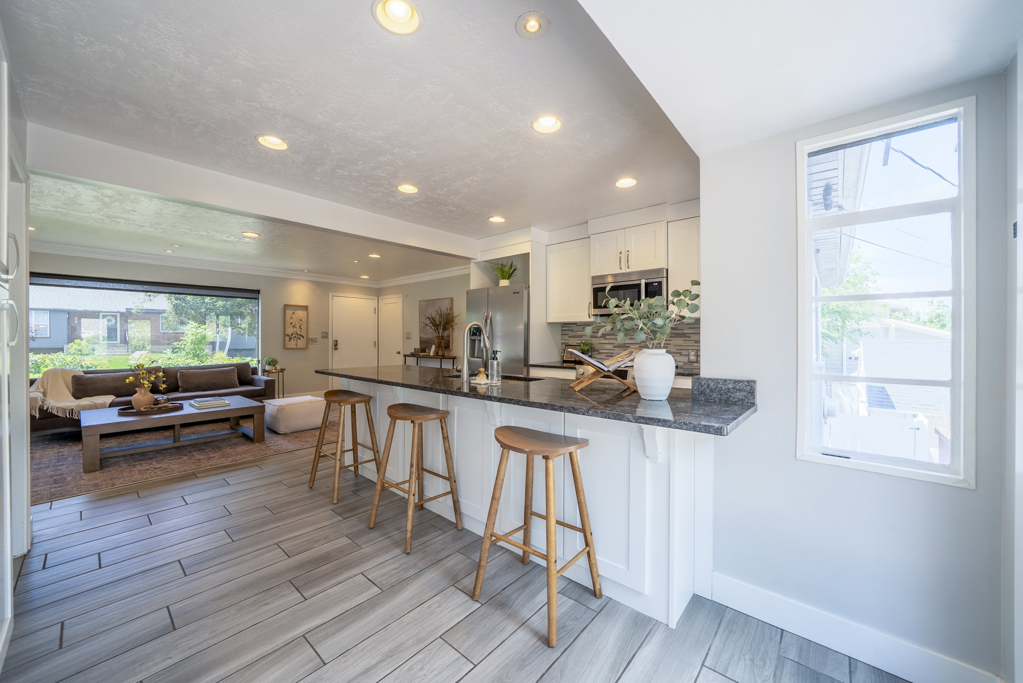 Kitchen island with bar seating, integrated stainless steel sink, and dark stone countertop